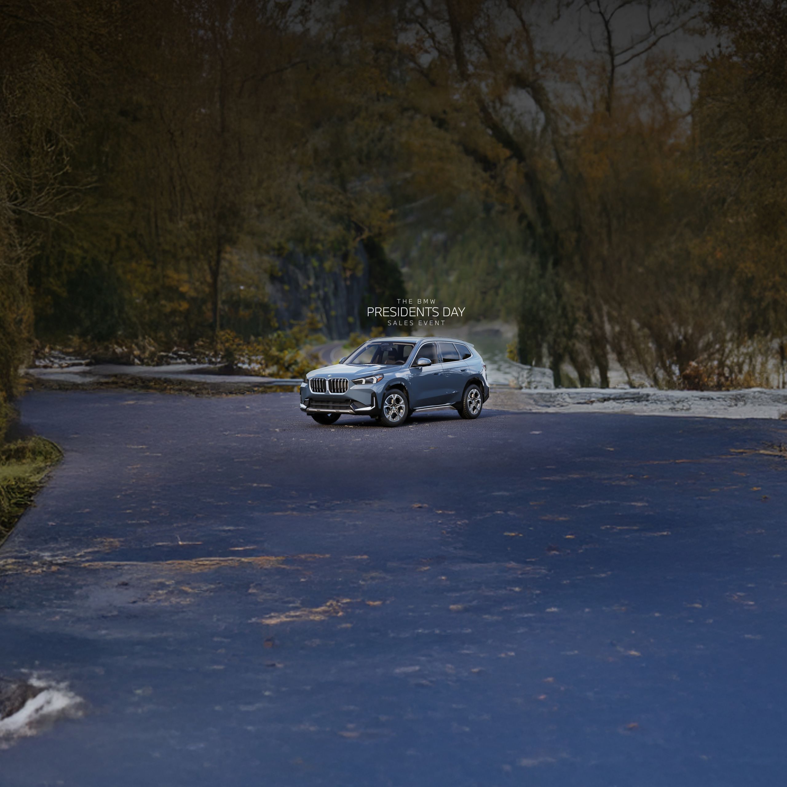 A BMW X1 sits parked on a road with cliffs and a river in the background
