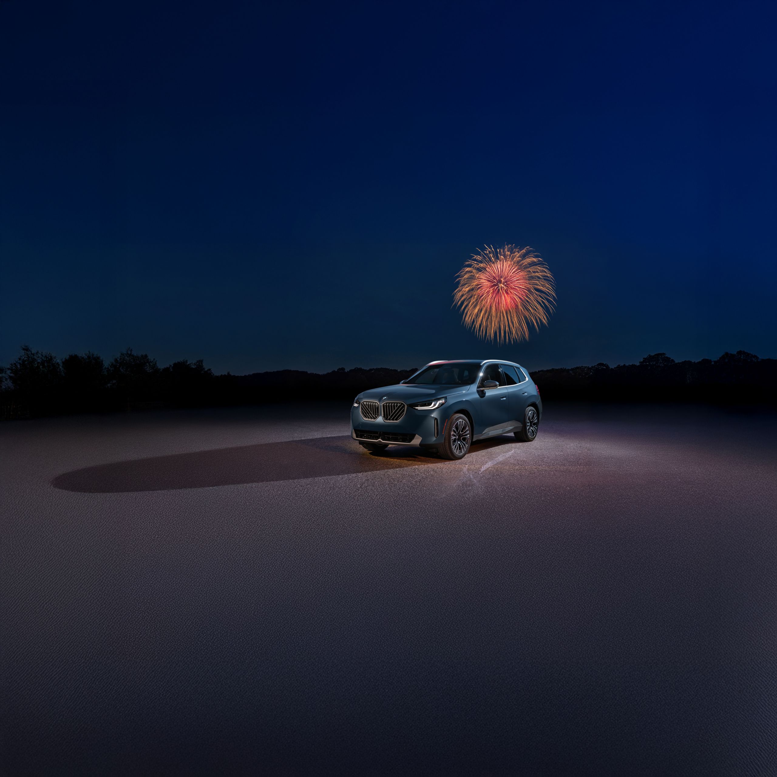 A BMW X3 30 xDrive parked at night with fireworks in the background.