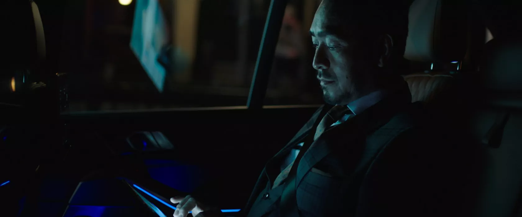 Man riding in back of BMW at night.