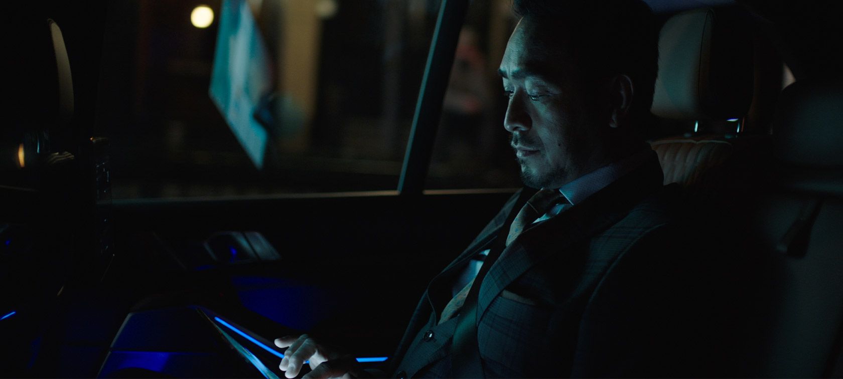 Man riding in back of BMW at night.