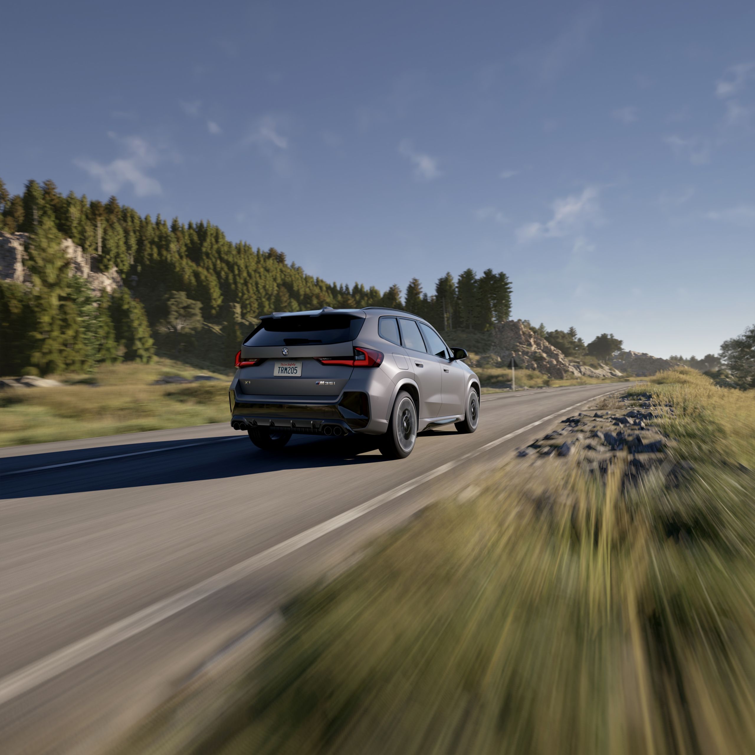 Rear shot of the 2026 BMW X1 M35i driving down a road road in a forrest setting.