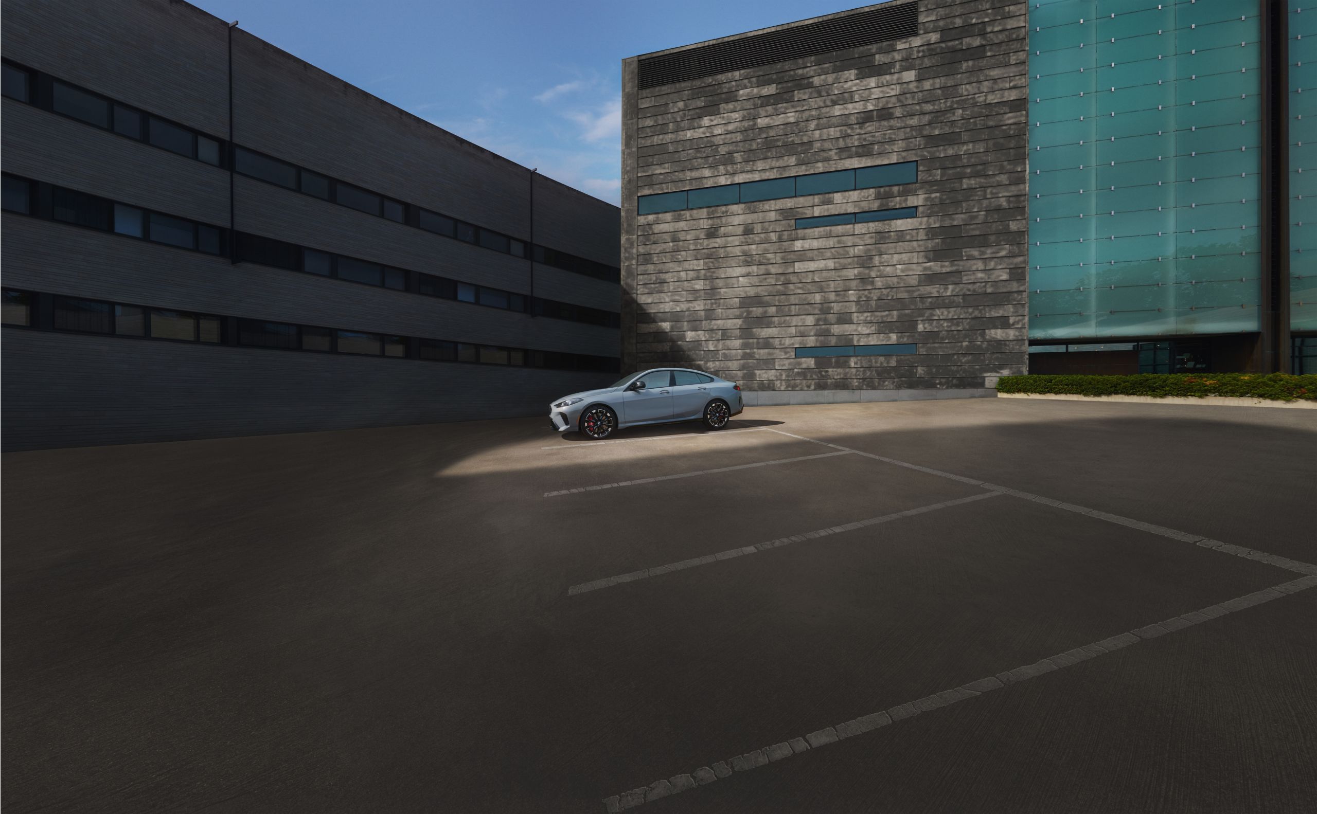 A BMW 5 Series parked on a brick street outside a modern urban building.