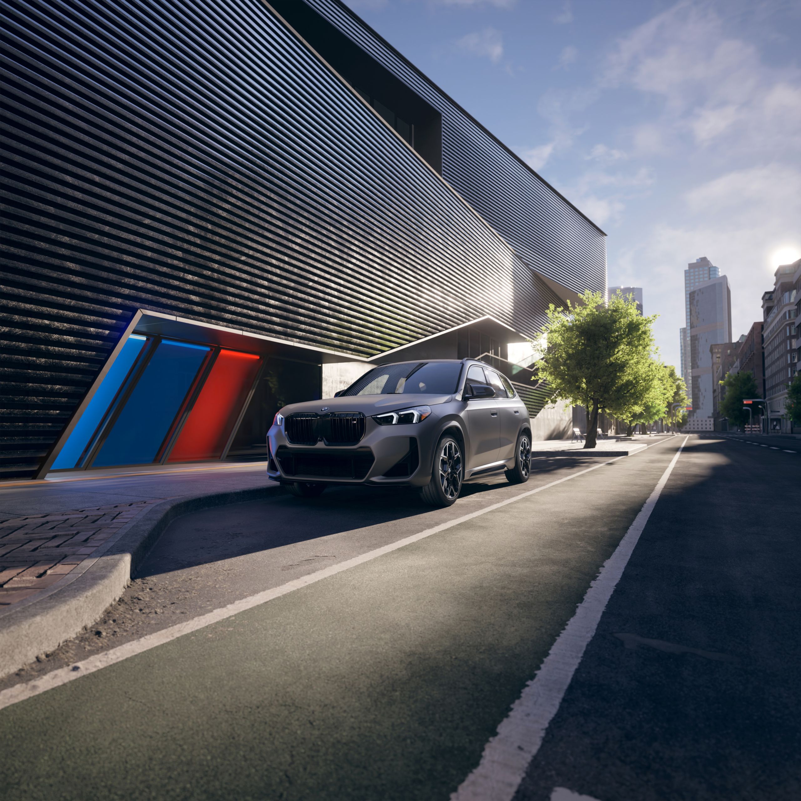 A matte gray 2026 BMW X1 M35i SUV parked in front of a modern building with architectural lines that make up the BMW M series logo.