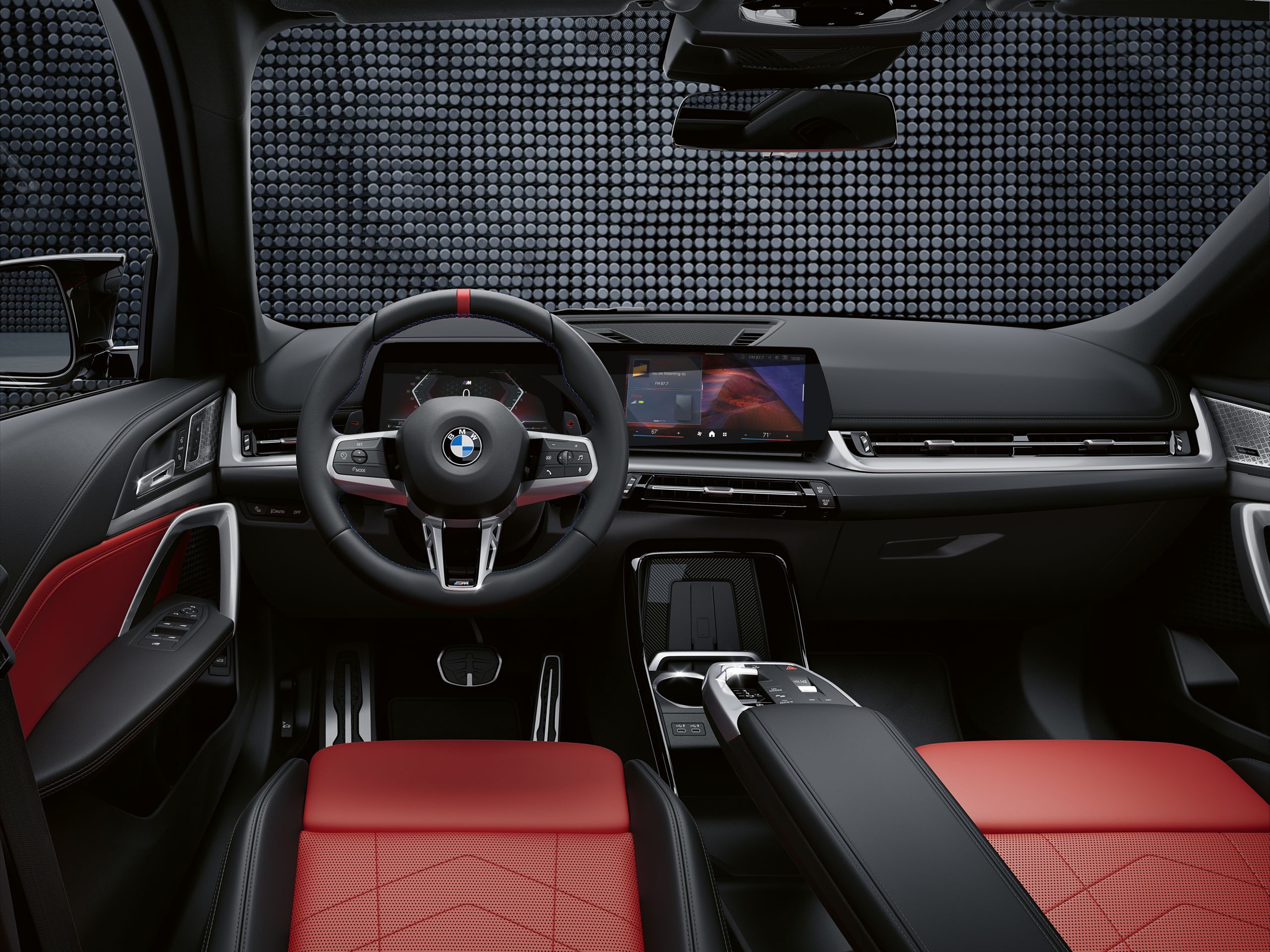 Close up interior shot of the BMW X1 M35i's M steering wheel with a bold grip, signature red 12 o’clock marker, M color stitching and paddle shifters