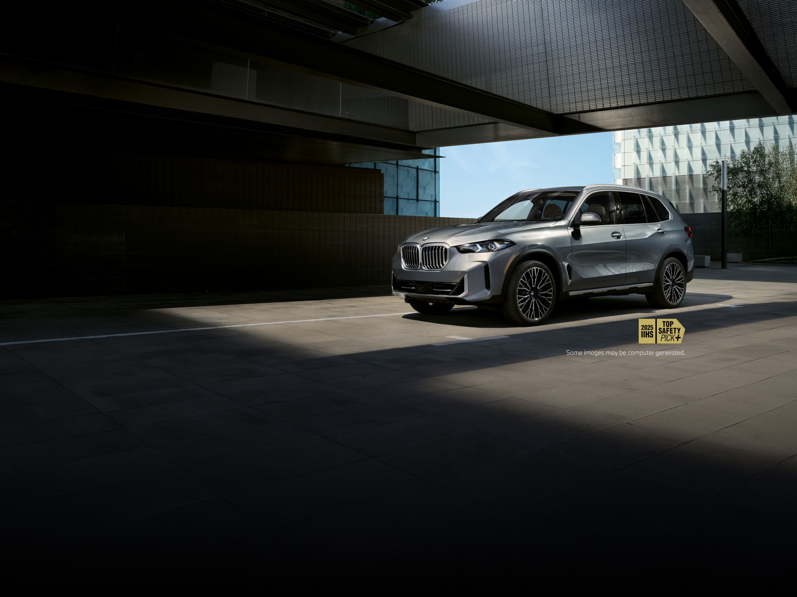 The BMW X5 parked on an elevated grey structure in front of a blue sky.