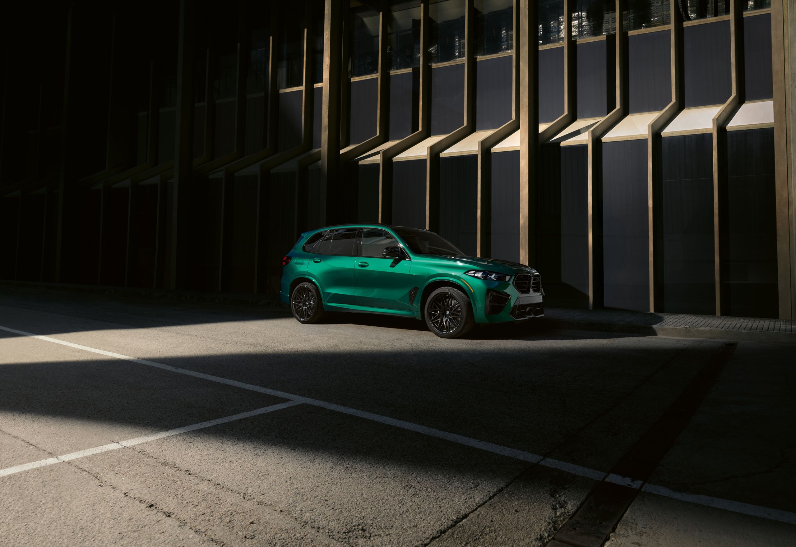 A side profile shot of the BMW iX parked on a city street with lush foliage behind it