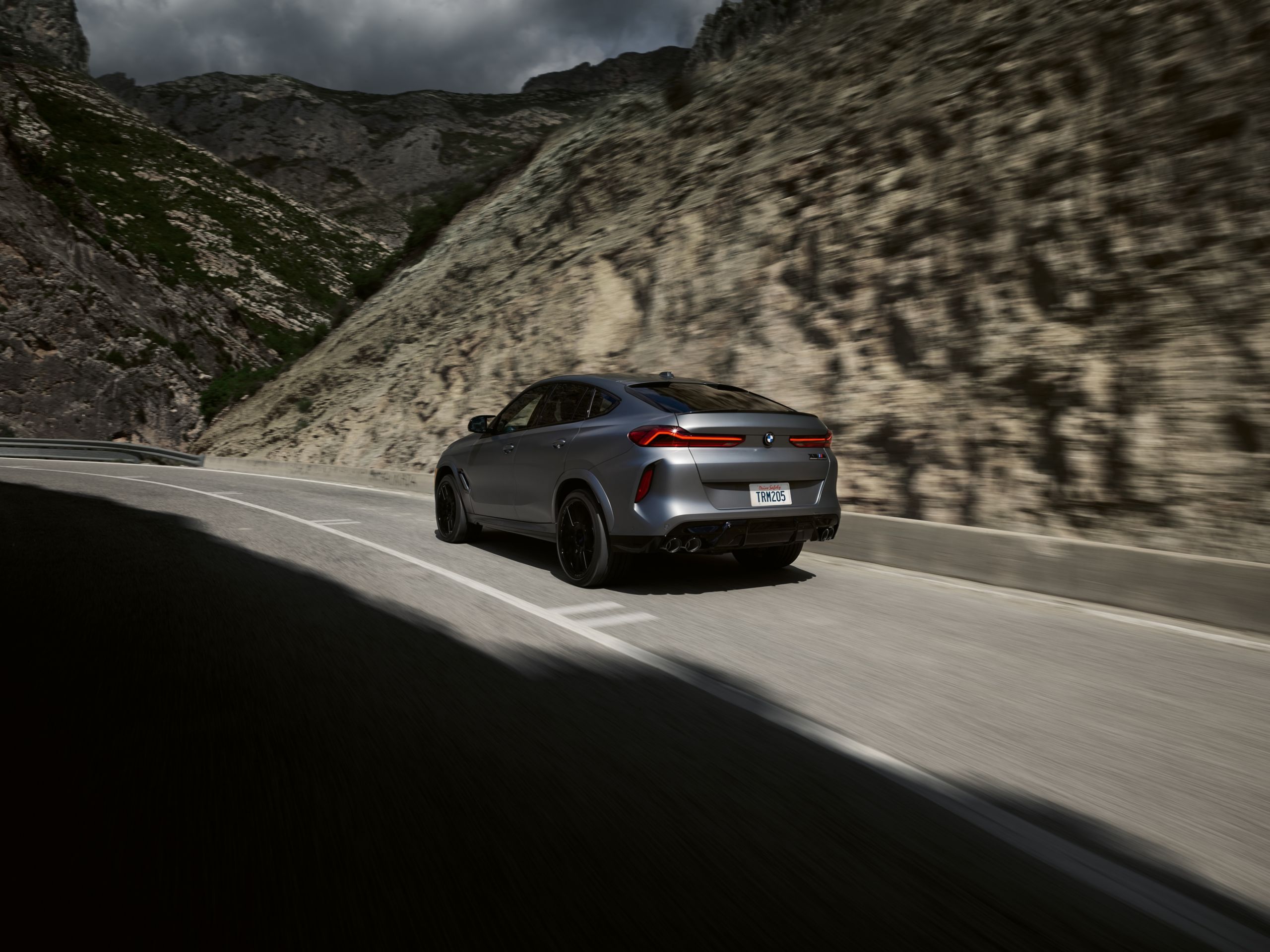 BMW X6 M Competition driving on a country road through a valley