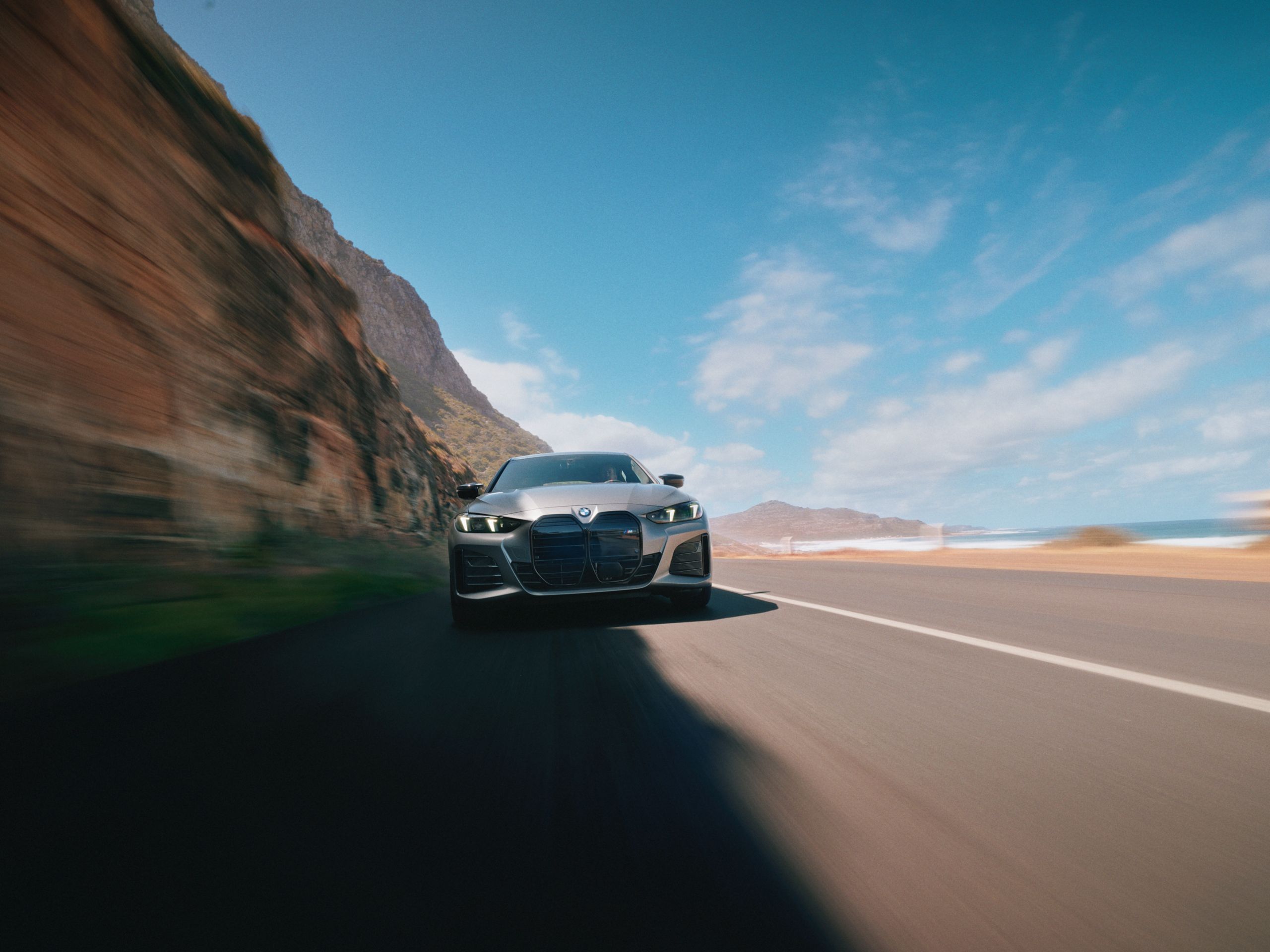 A frontal shot of the BMW i4 as it drives down a desert canyon highway