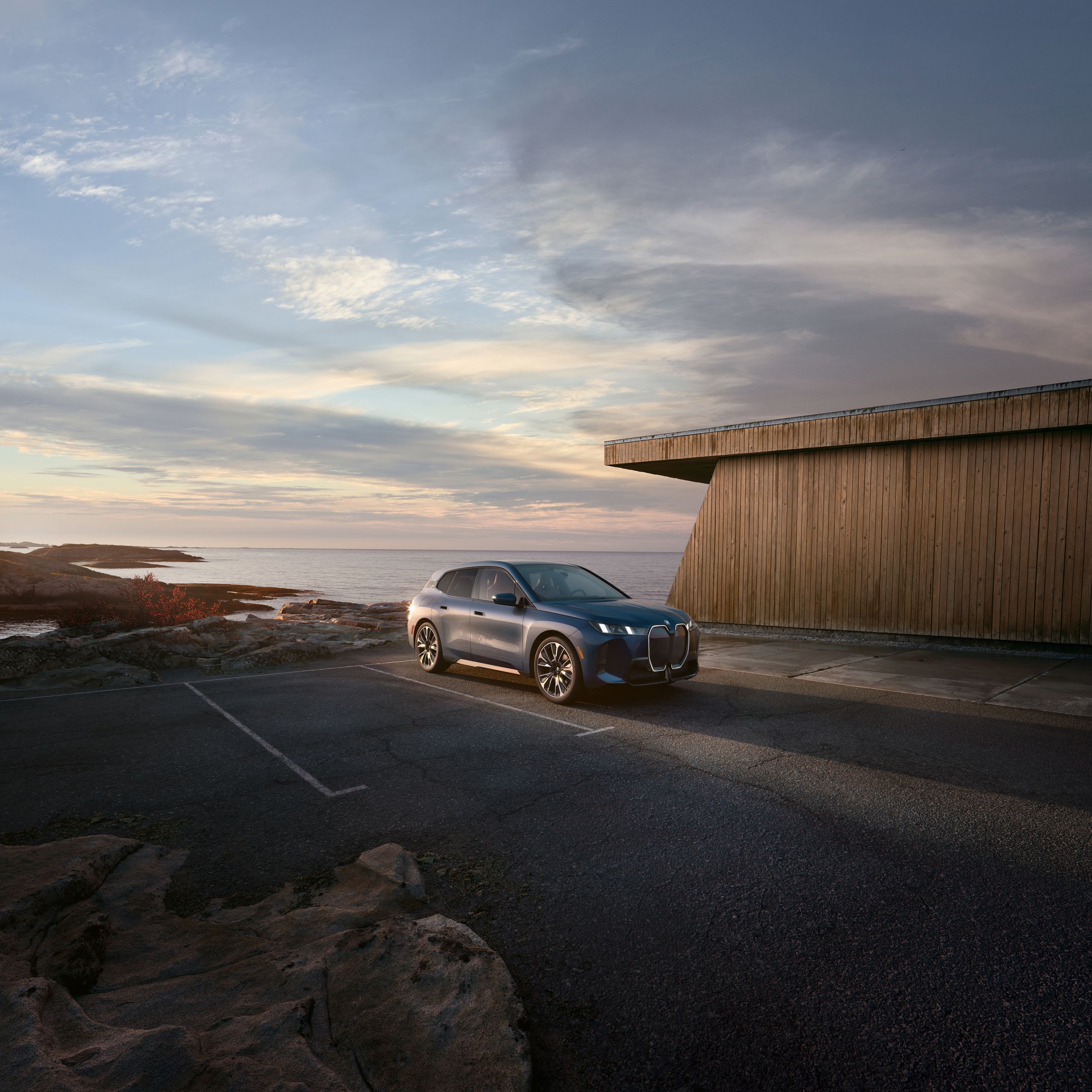 The BMW iX parked in a coastal area around sunset