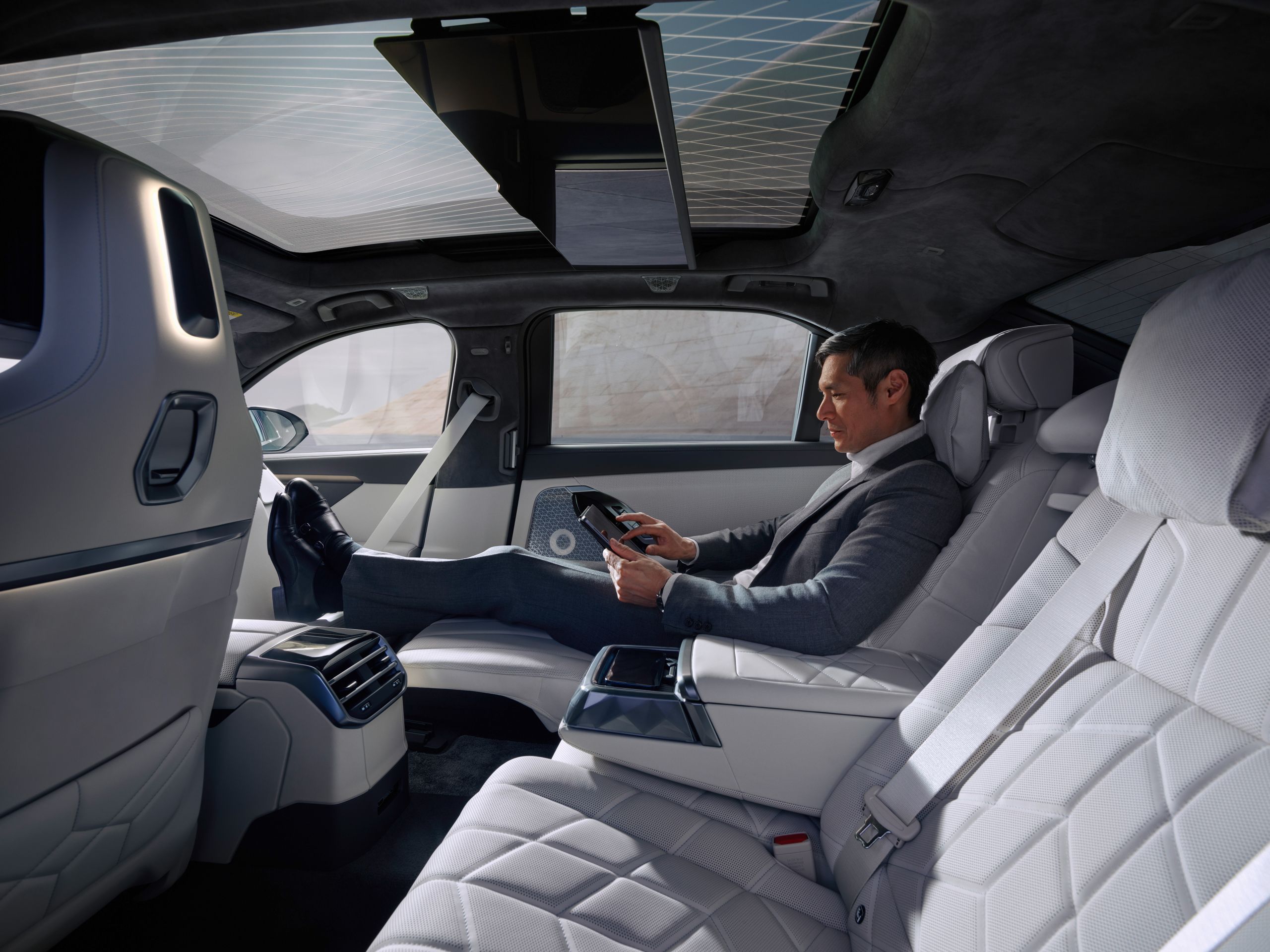 A person sits in the rear in the Executive seat position and uses a tablet.