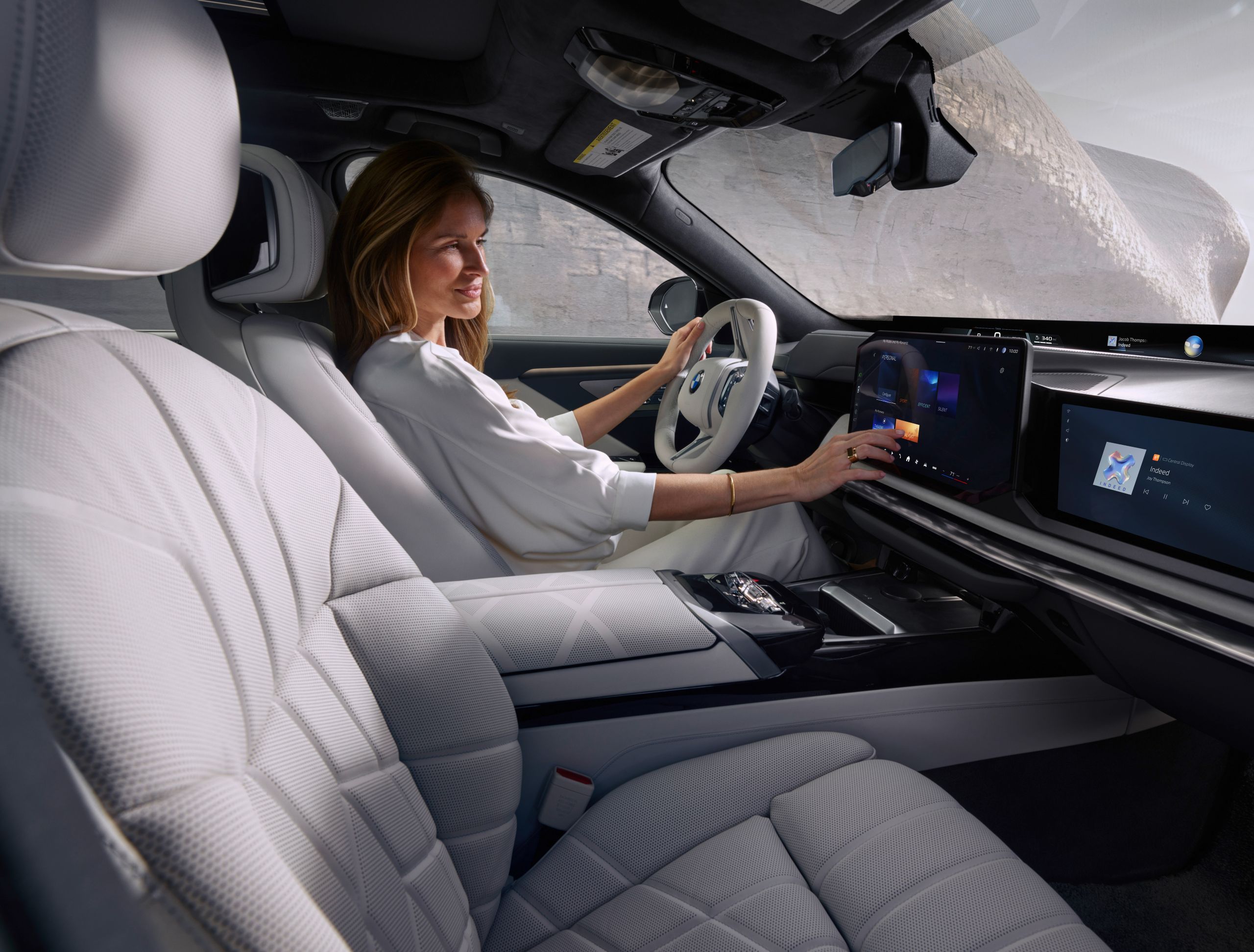 A person is driving and operating the central information display.