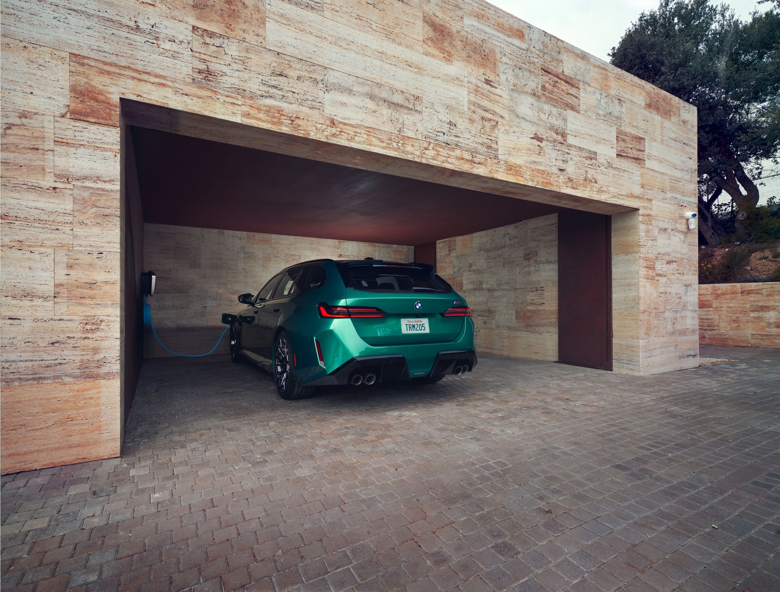 BMW M5 Touring charging in a garage.