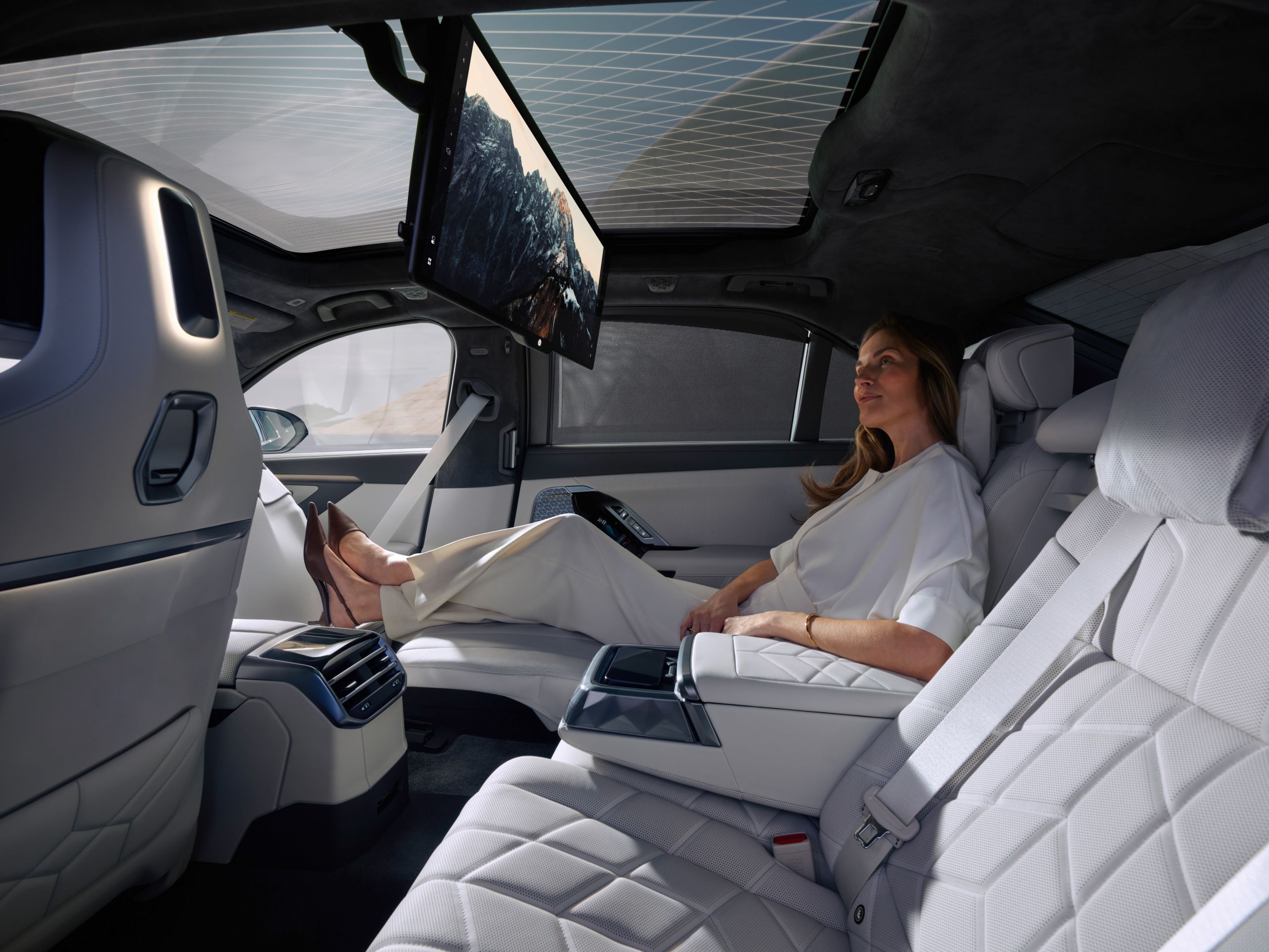 A person sits in the rear and watches a movie on the BMW Theatre Screen.