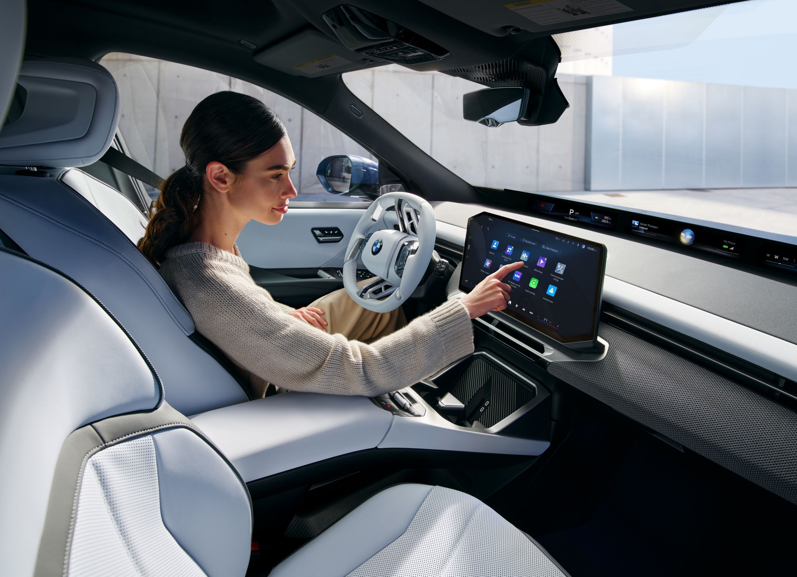 A person is operating the central display in the BMW iX3
