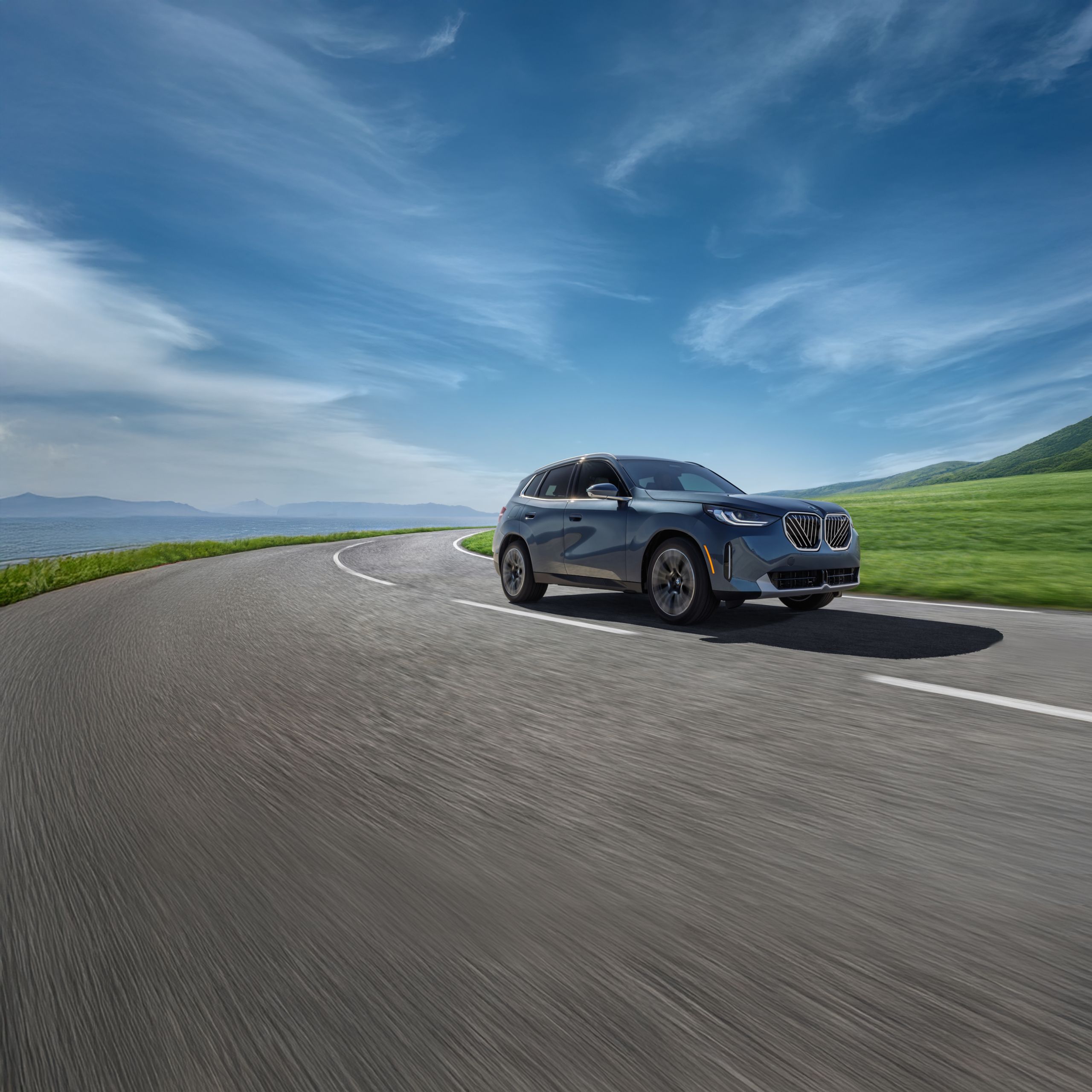 The BMW X3 30 xDrive driving down an open road with a blue sky in the background.