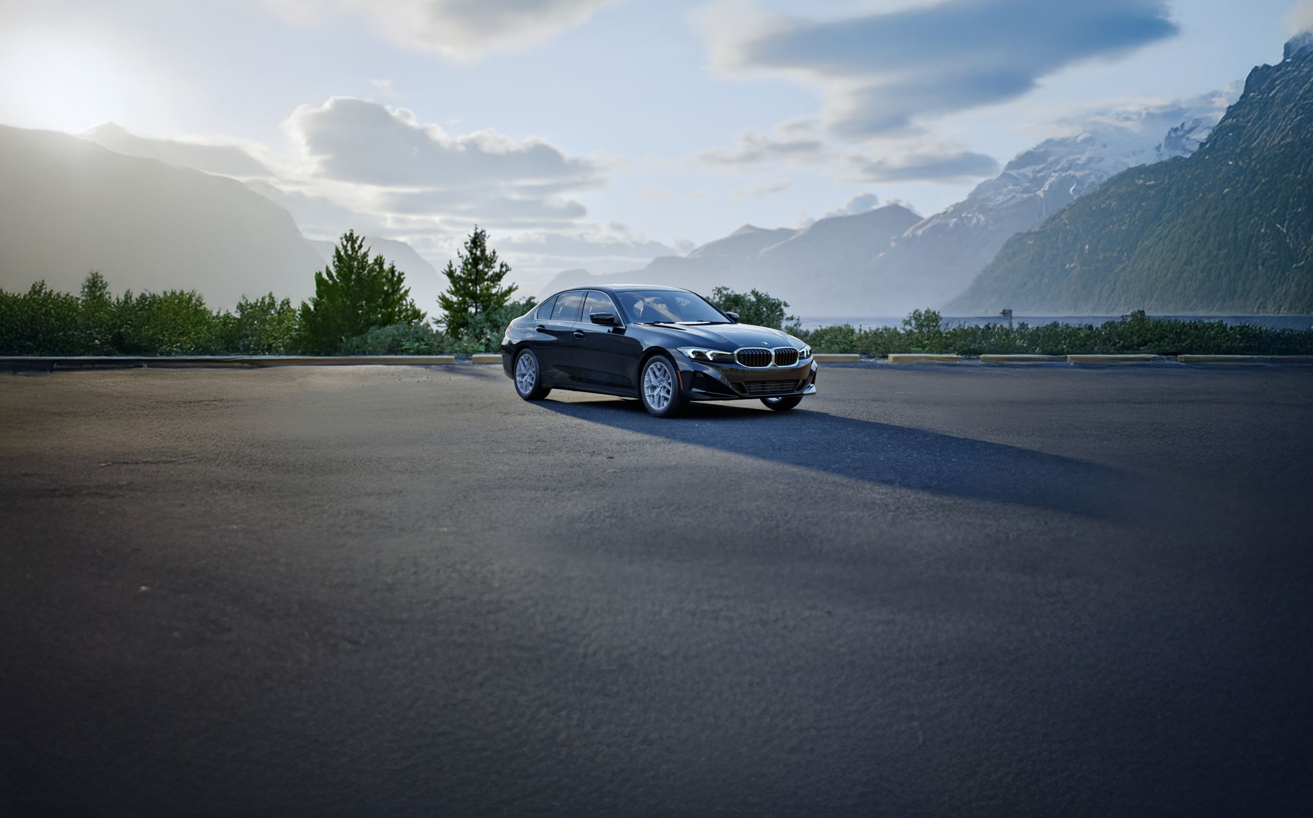 The BMW 330i parked in a scenic parking lot overlooking trees, mountains, and a blue sky.