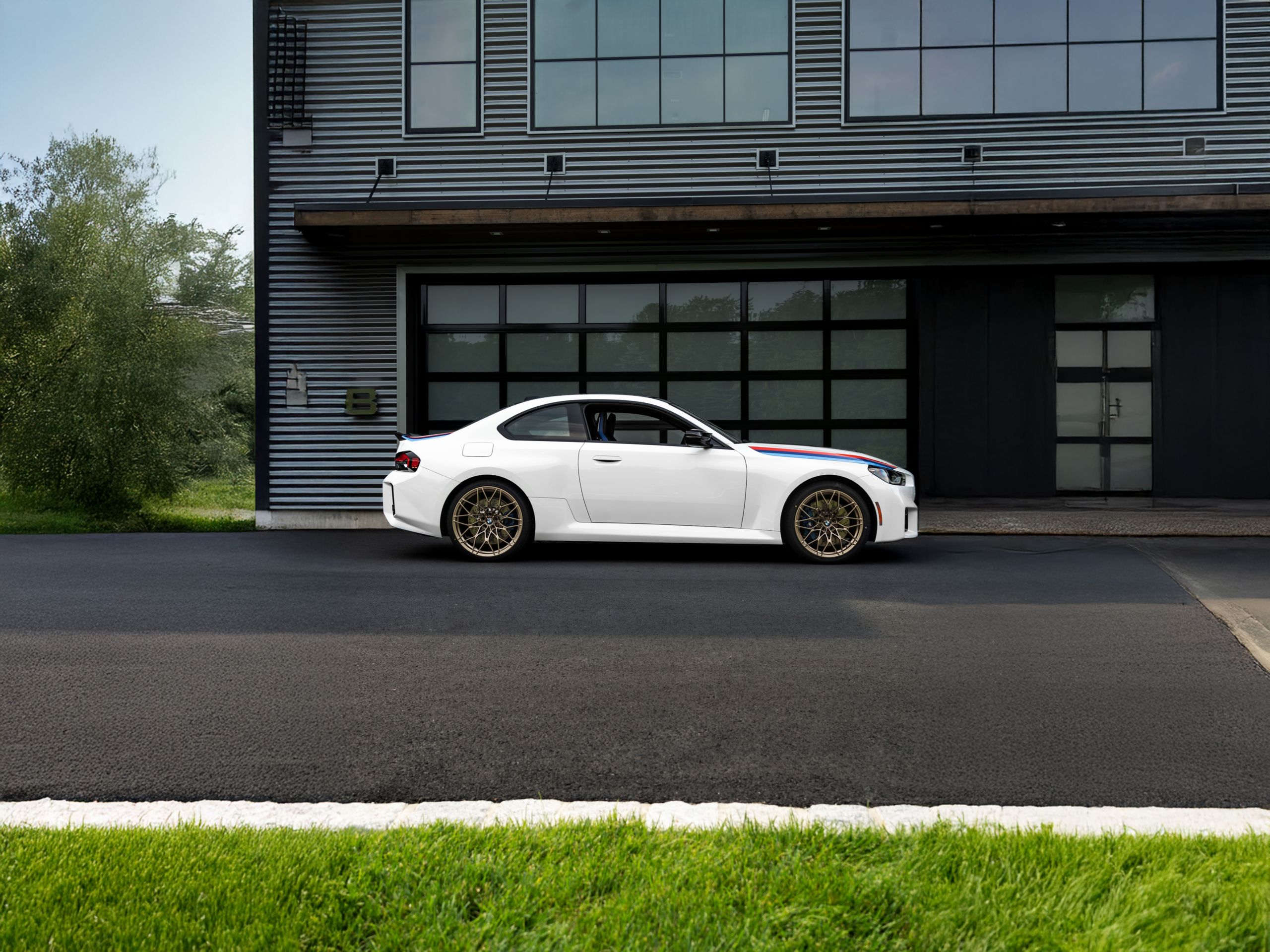 Side profile of the BMW M2 Turbo Design Edition parked in front of a modern industrial door 