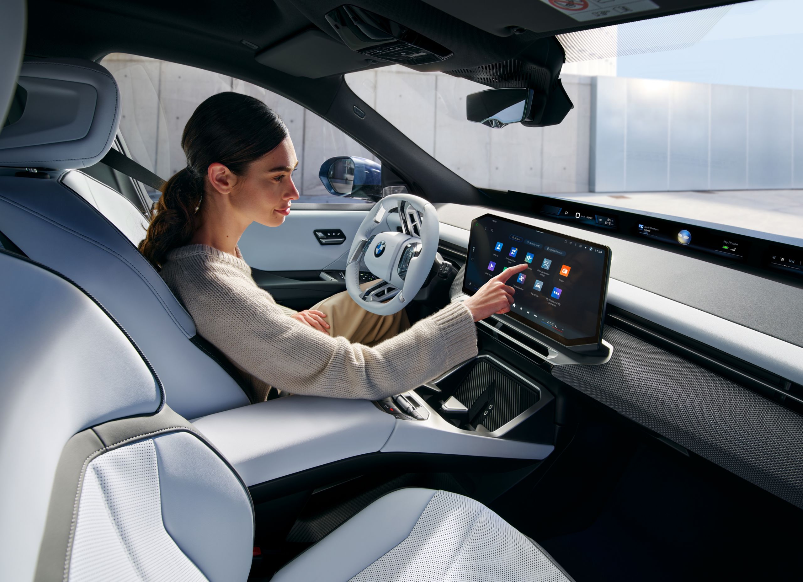 A person is operating the central display in the BMW iX3