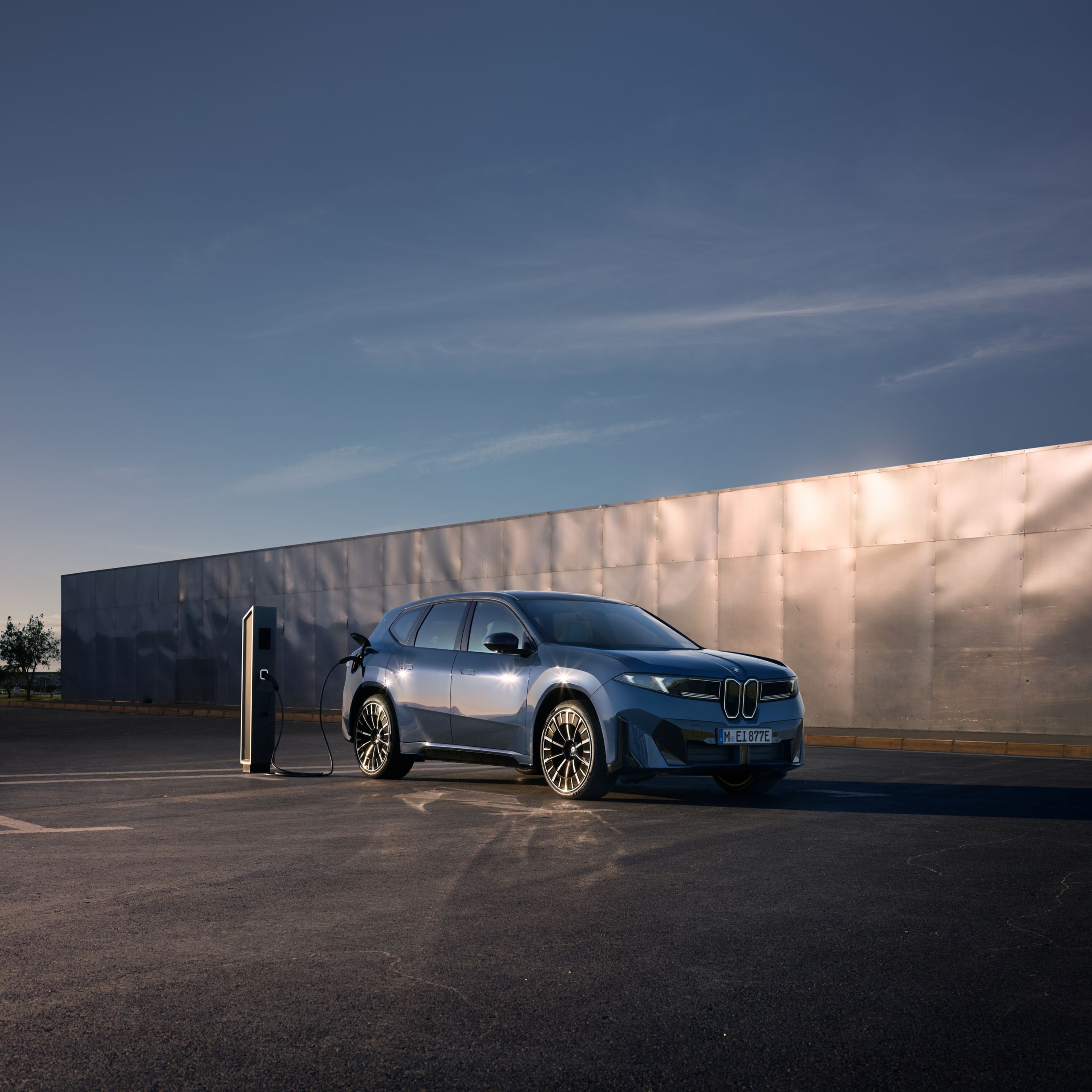 A BMW iX3 is being charged at a public charging station