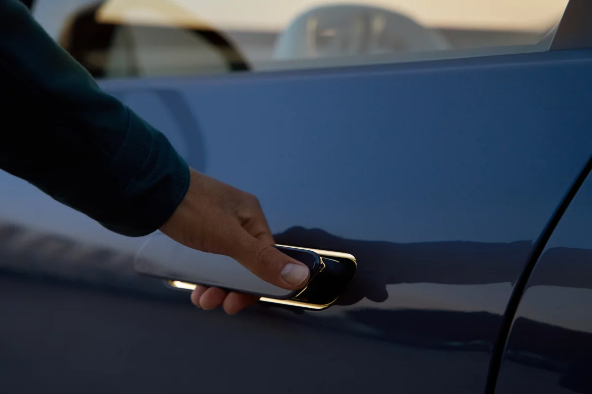 A person using the illuminated, extended door handle of the BMW iX3