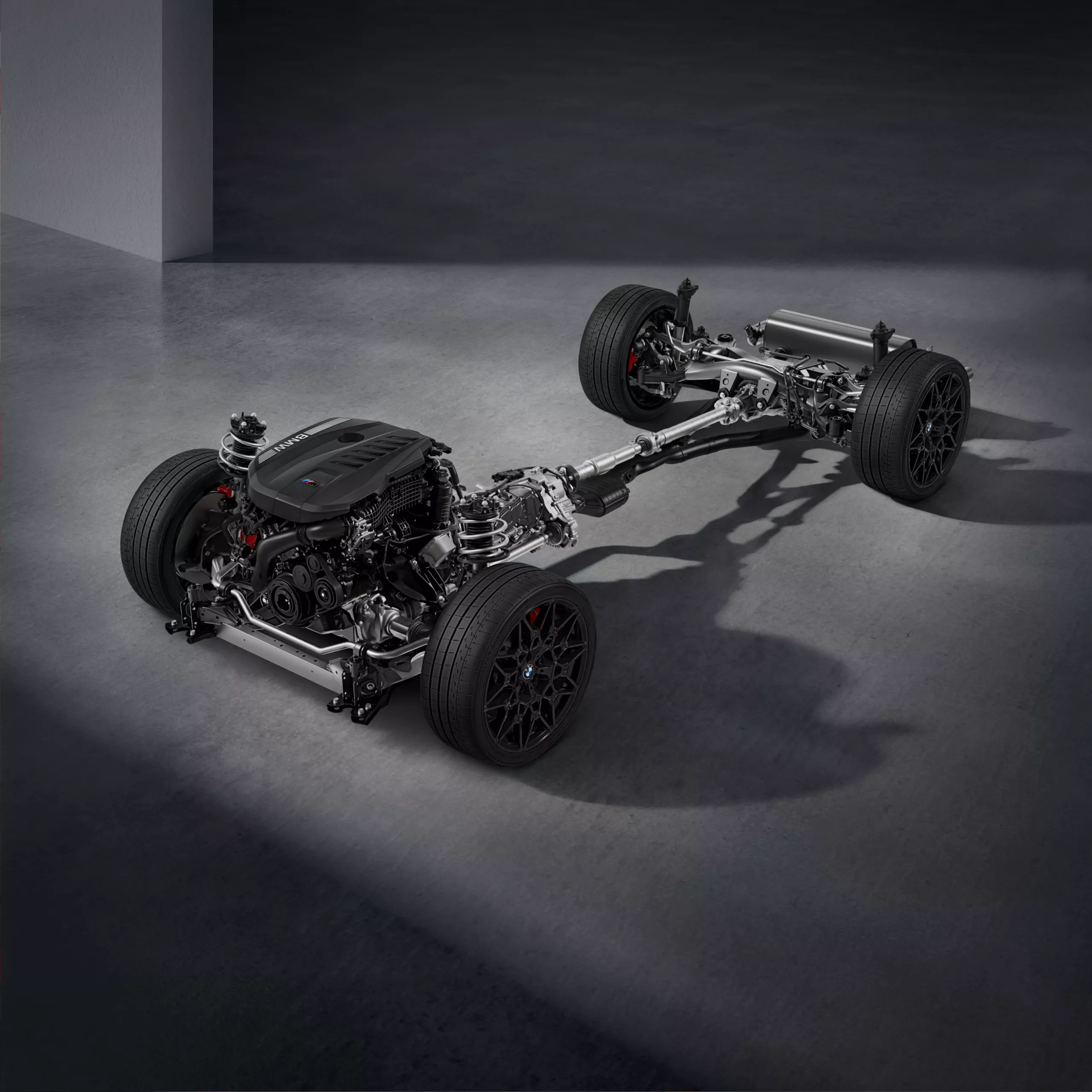 Powertrain featuring an BMW M TwinPower Turbo inline 6-cylinder petrol engine, gearbox and rear axle on a grey background.