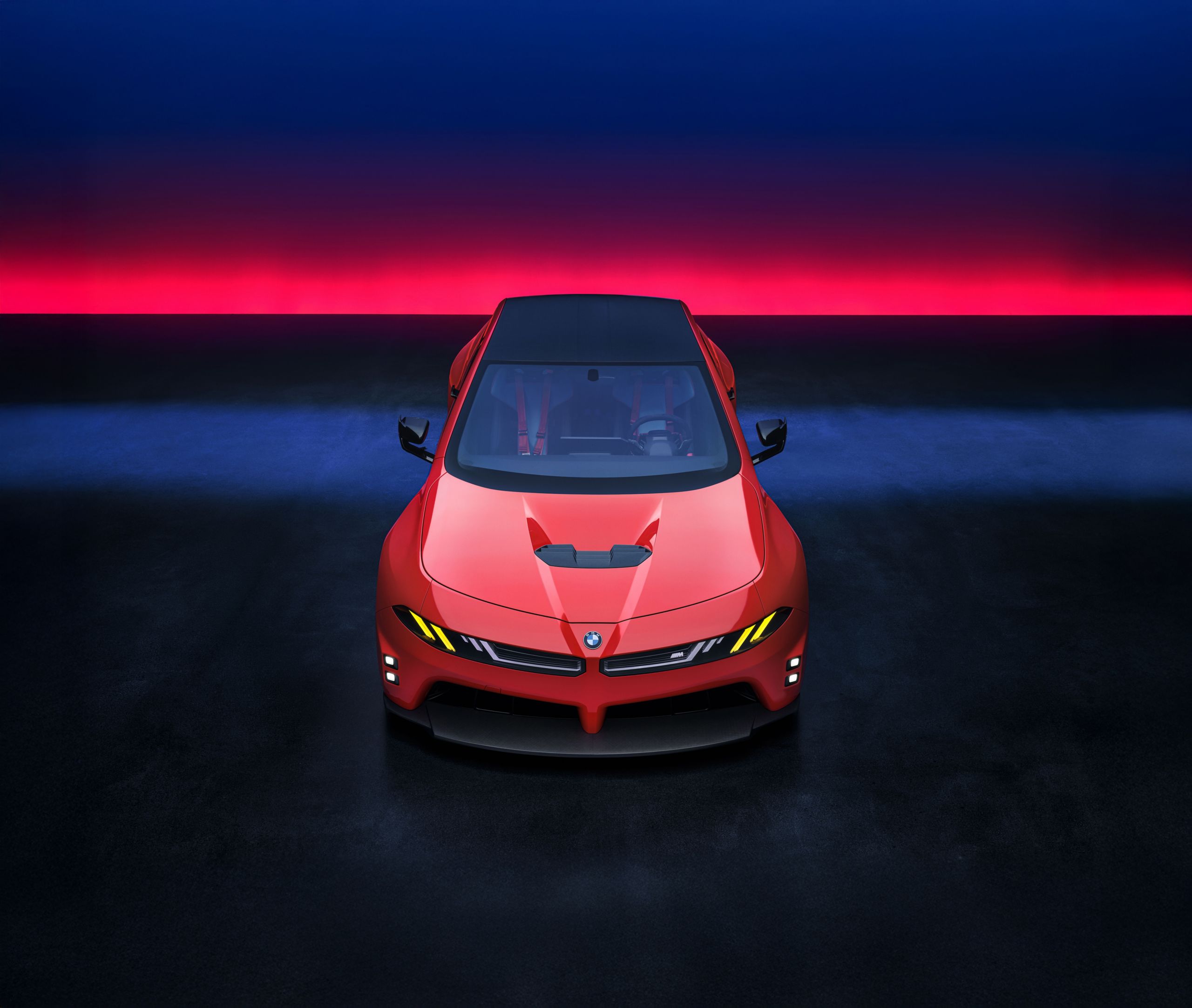 A high angle shot of the BMW M Concept Neue Klasse in a red and blue studio space.