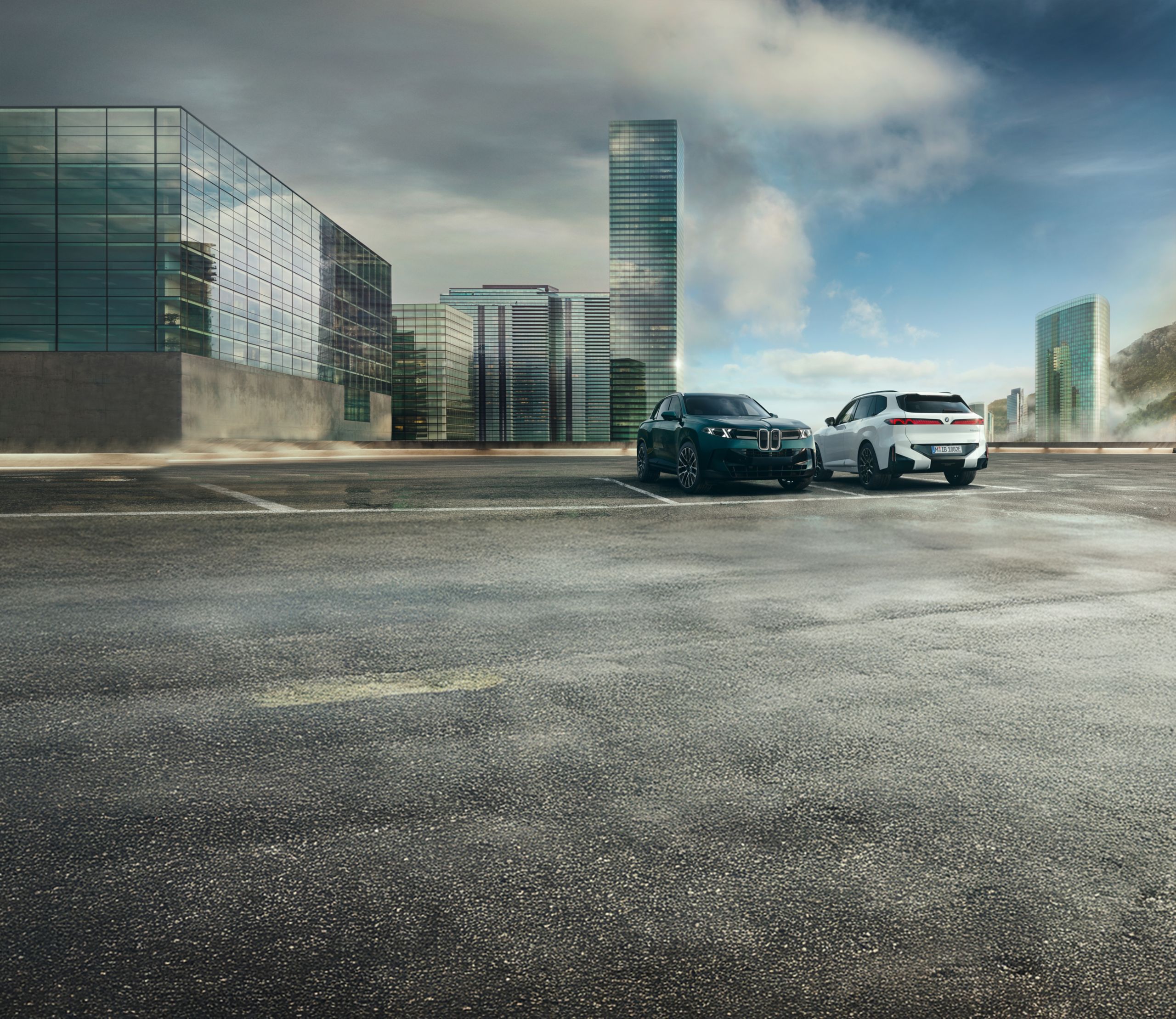 The BMW X5 40 xDrive and X5 50e xDrive sit parked on a rooftop parking lot amidst an urban environment.