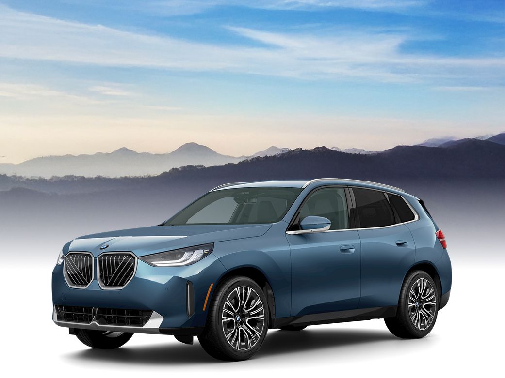 A BMW X3 with a silhouetted landscape and vast blue sky in the background