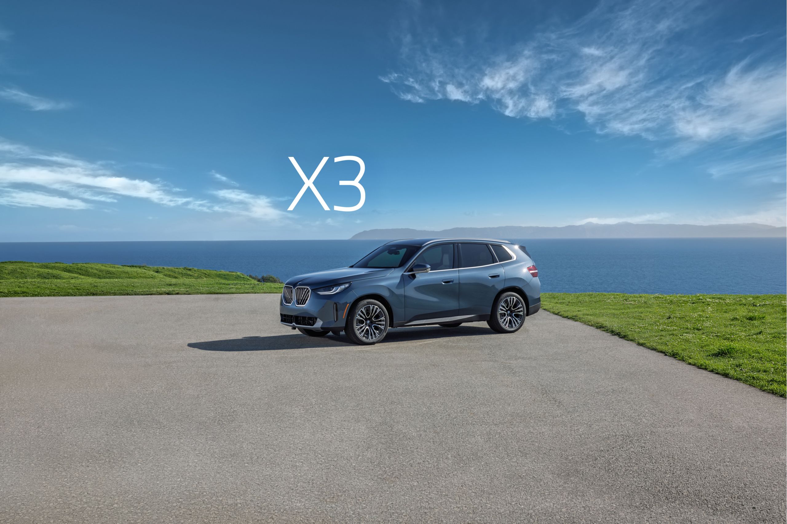 The BMW X3 parked on a paved area in front of a large body of water.
