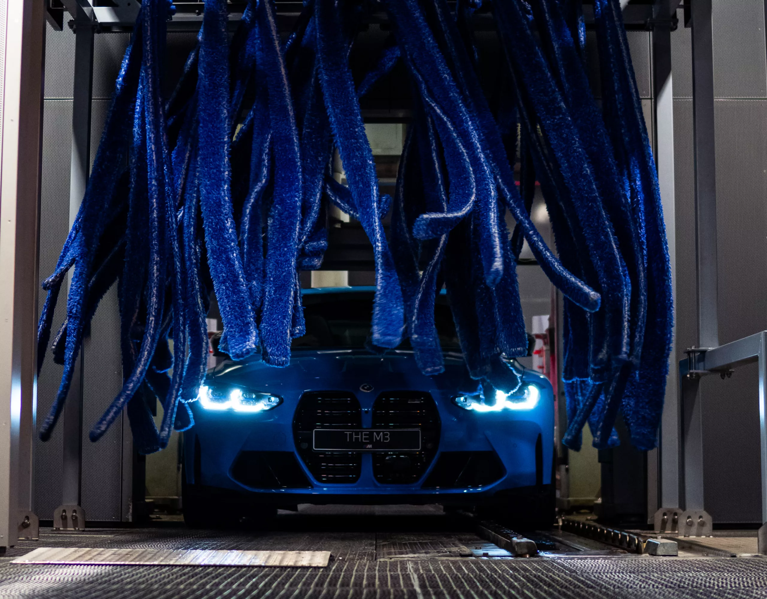 Blue BMW gets a cleaning in the car wash.