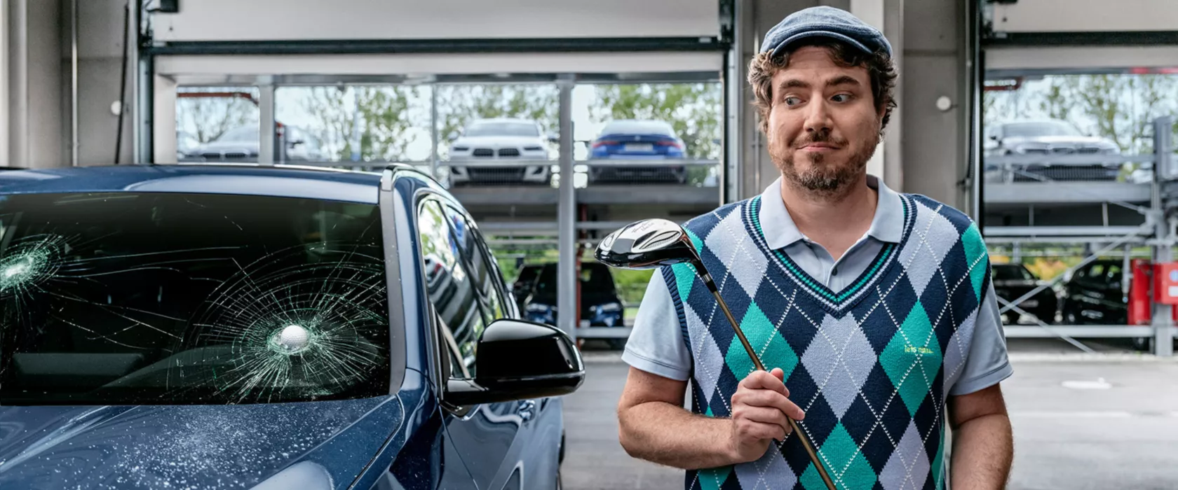 Mand, som holder en golfkølle ved siden af en BMW, der er blevet ramt af en golfbold i frontruden.