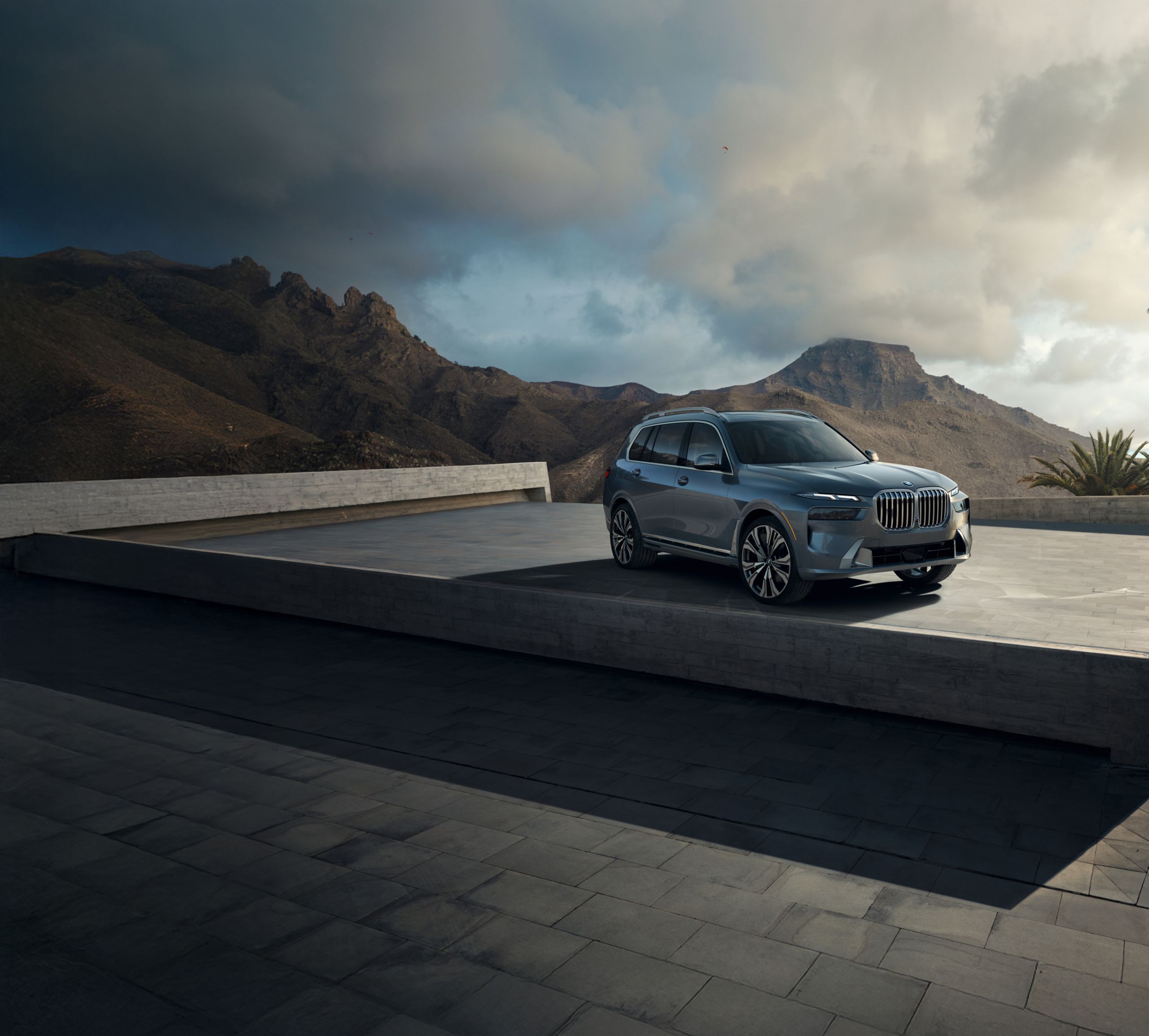 The BMW X7 xDrive 40i parked on a modern sculptural platform against an arid desert landscape.