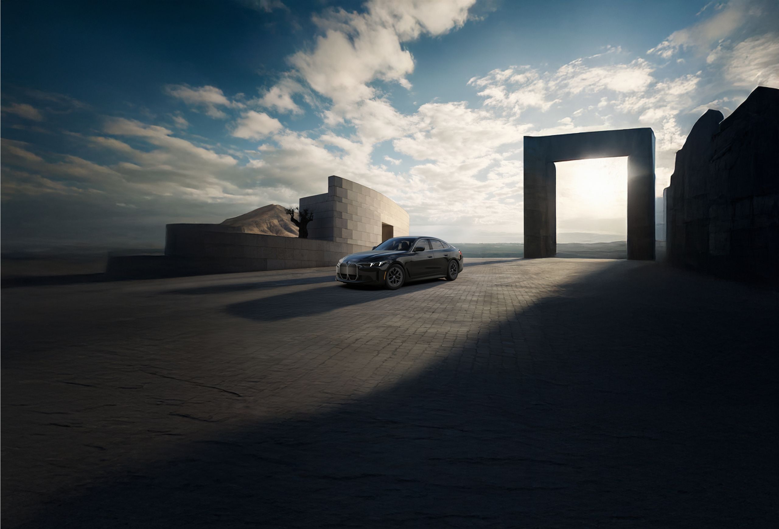 The BMW i4 eDrive40 parked in front of a scenic seascape on a cobblestone path.