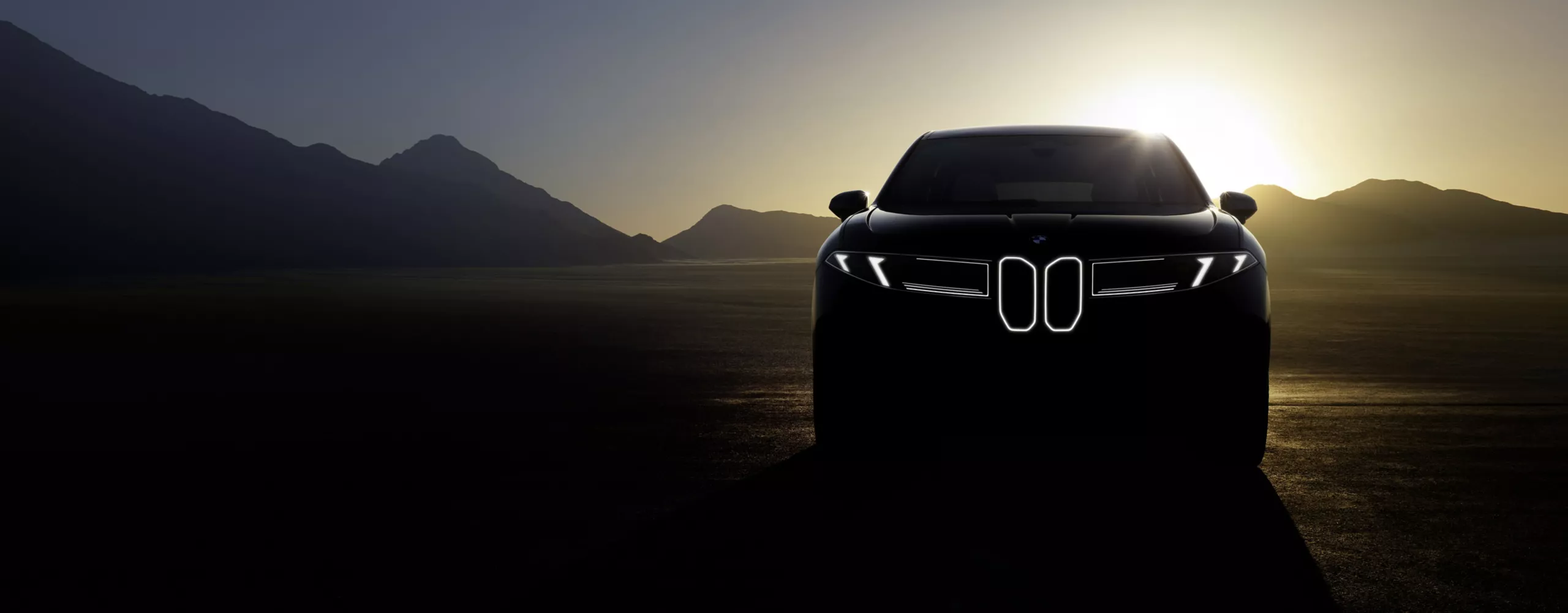Der neue BMW iX3 vor einer Bergkulisse bei Sonnenuntergang