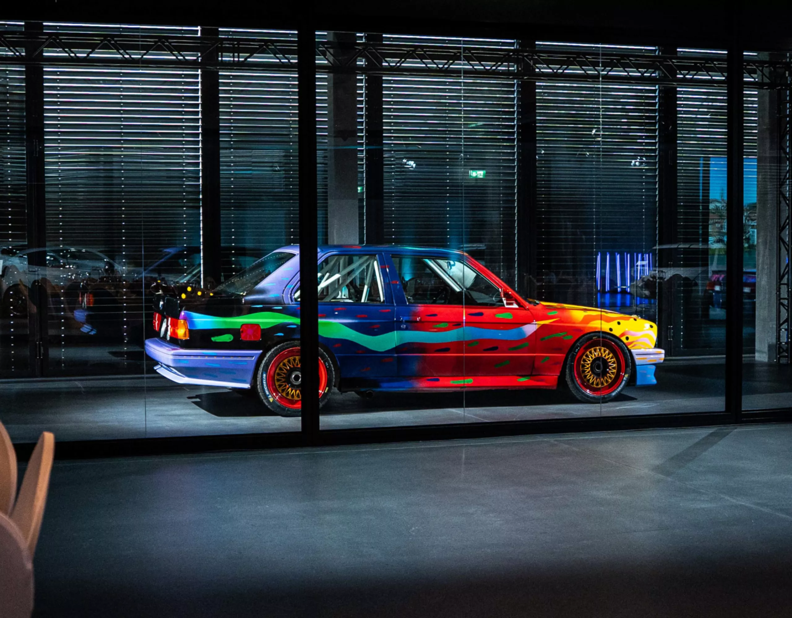 Vista laterale della colorata BMW Art Car no 8 cdi Ken Done illuminata da fari nel buio