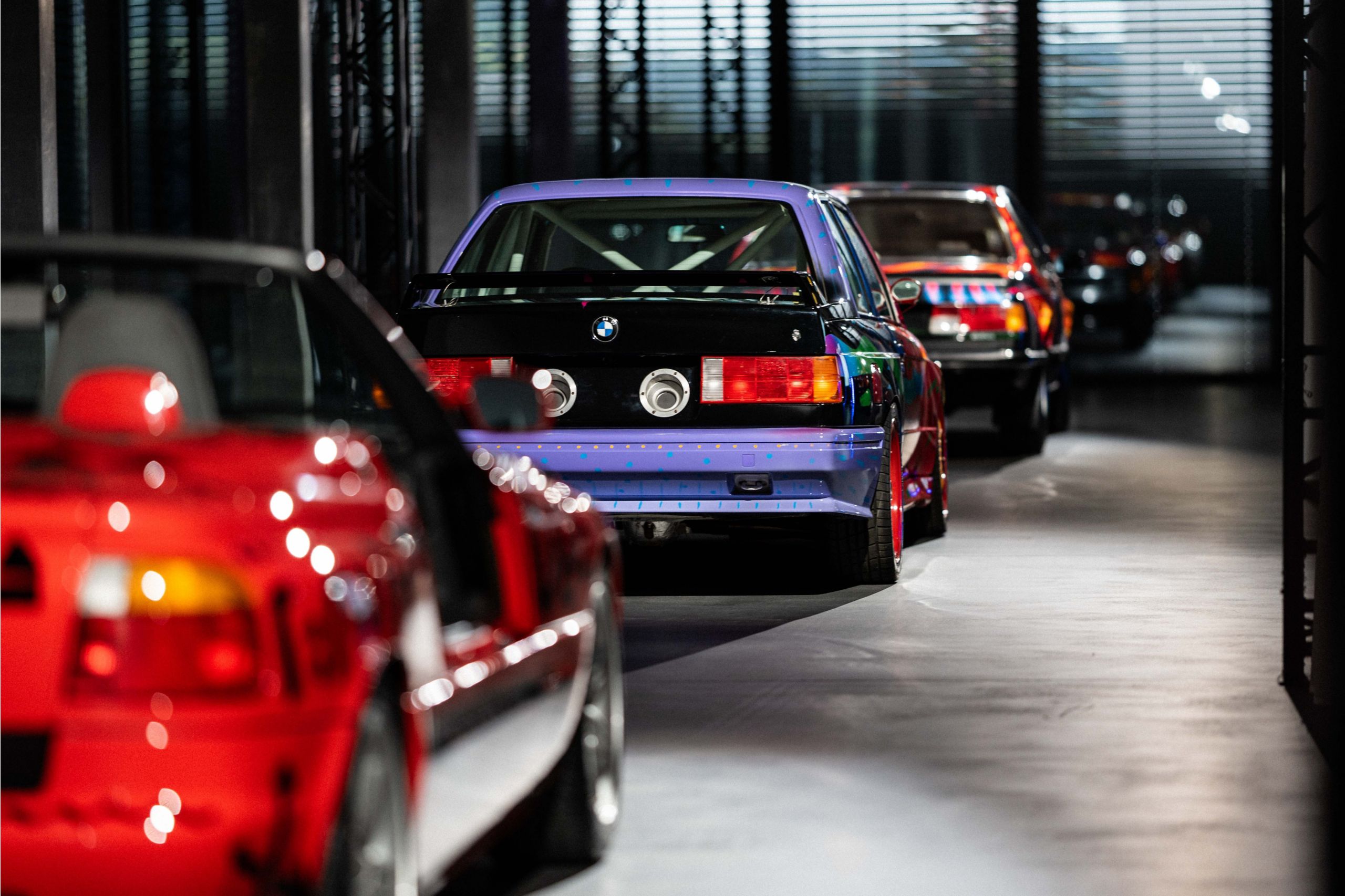 Six BMW Art Cars sont alignées les unes derrière les autres, vues de l’arrière