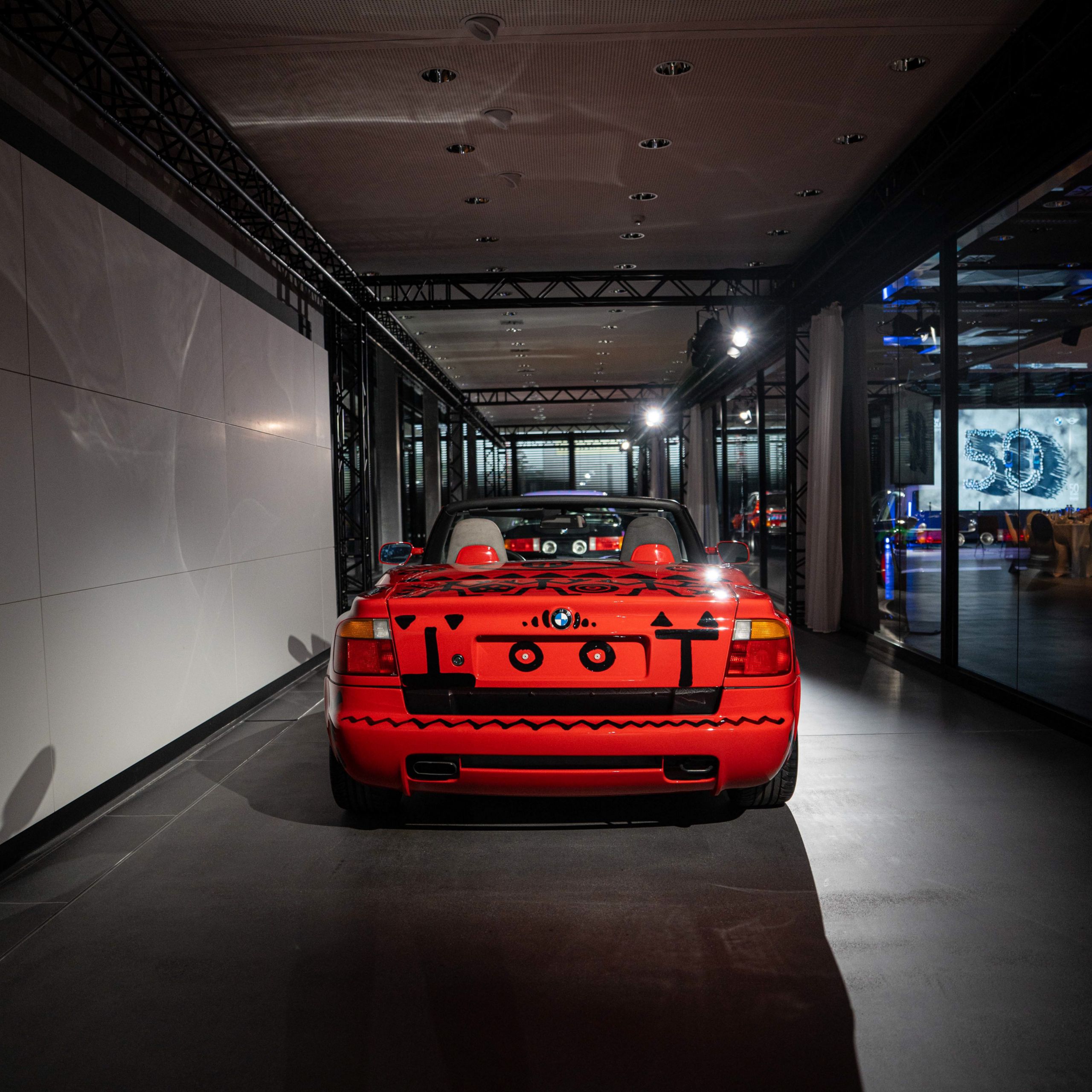 Vue arrière de la BMW Z1 Art Car rouge d’A.R. Penck avec des figures abstraites en noir
