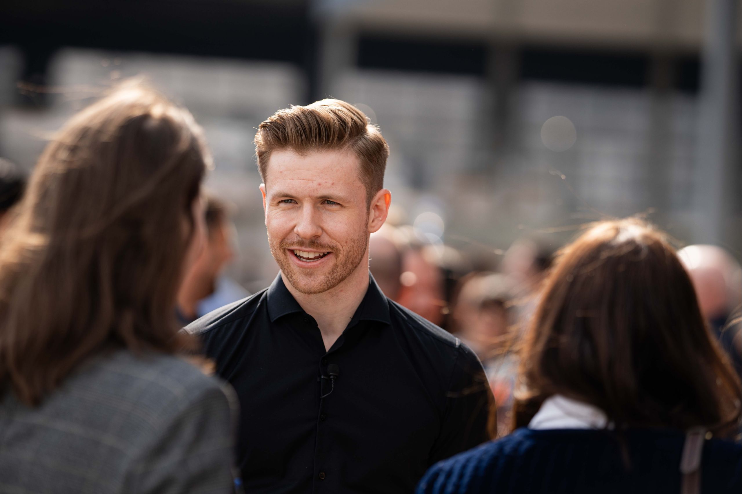 Un homme avec une chemise noire sourit pendant une interaction