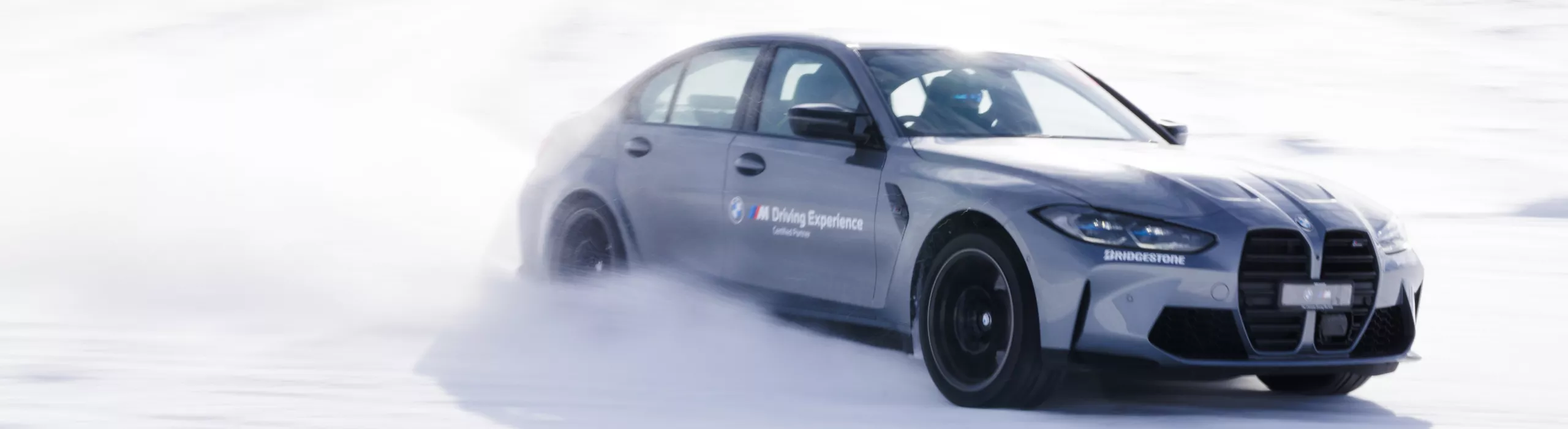 Silver BMW driving on a racetrack covered in snow