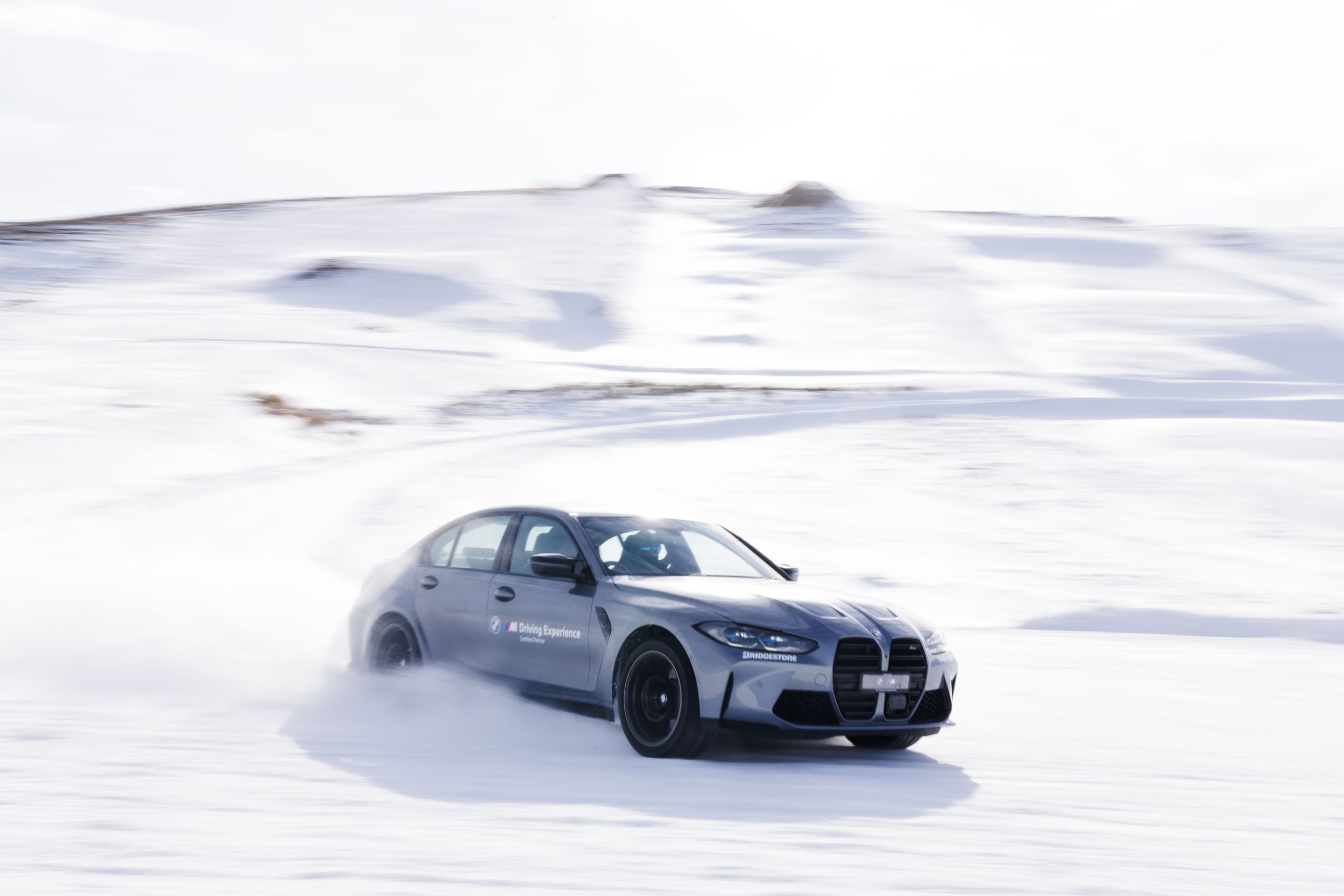 Silver BMW driving on a racetrack covered in snow