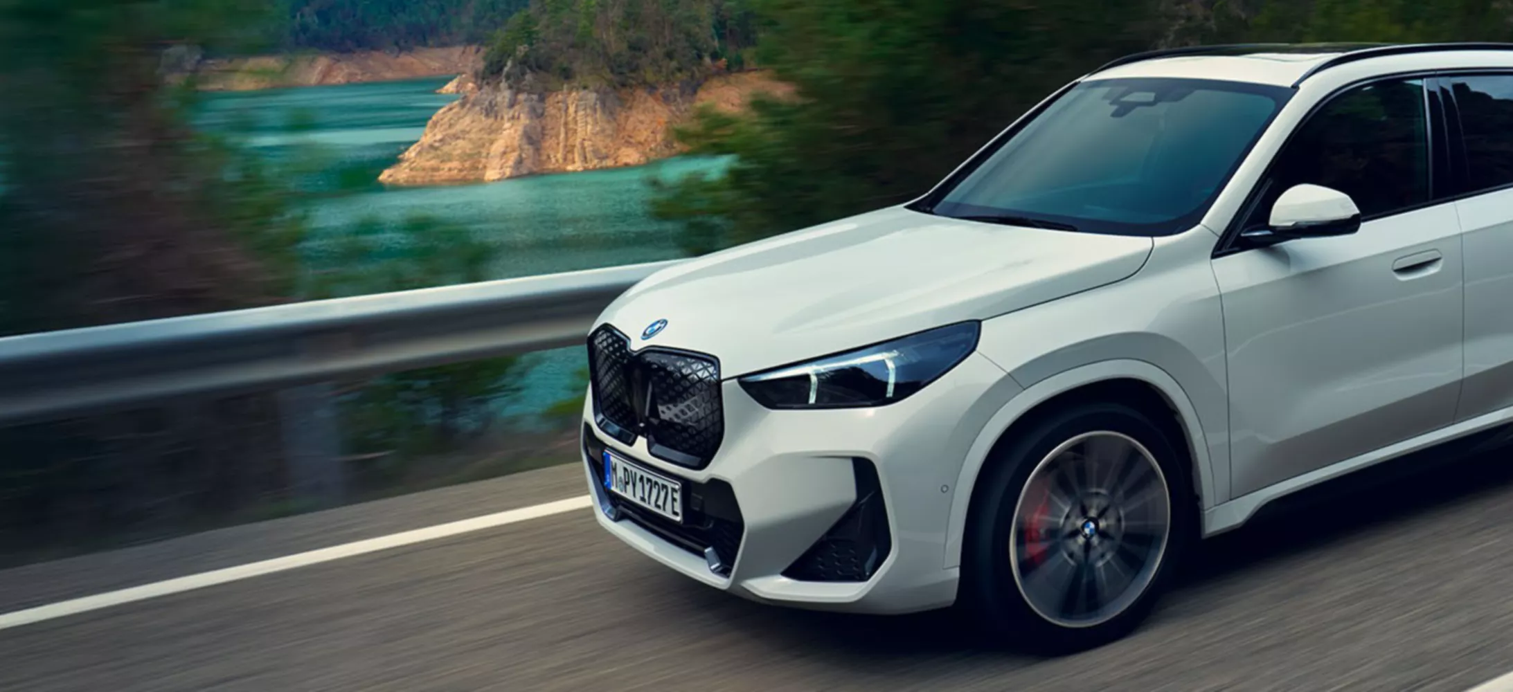 White BMW SUV driving on scenic mountain road
