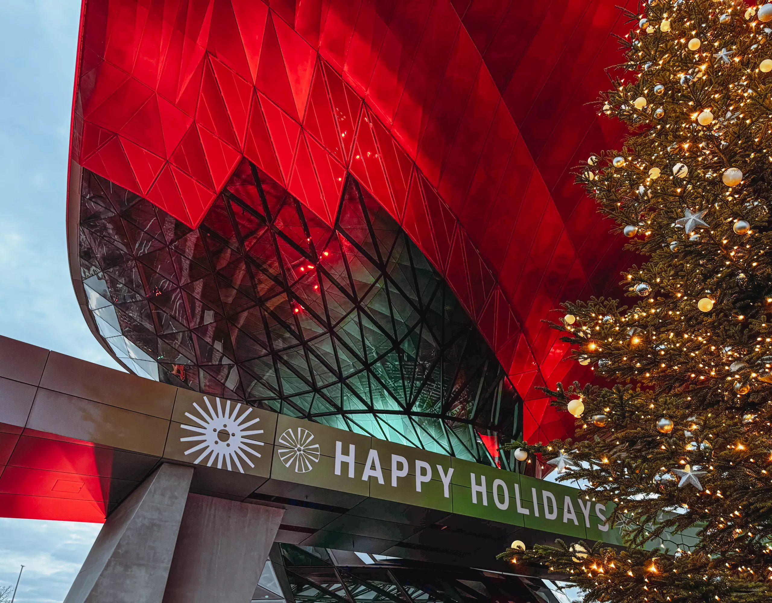 Red-lit Double Cone at BMW Welt with a Christmas tree and “Happy Holidays” lettering.