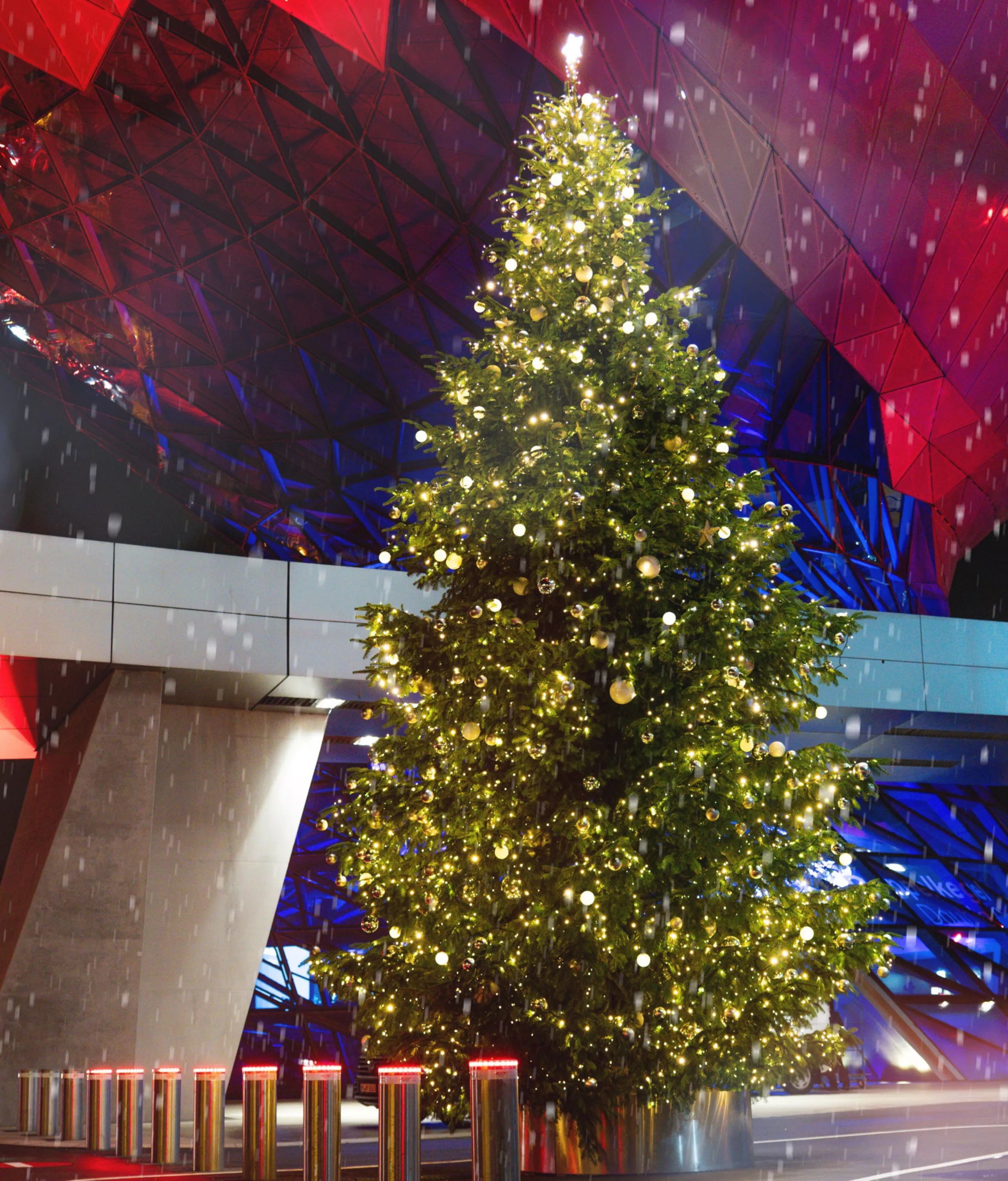 Christmas tree in front of the red-lit Double Cone at BMW Welt.