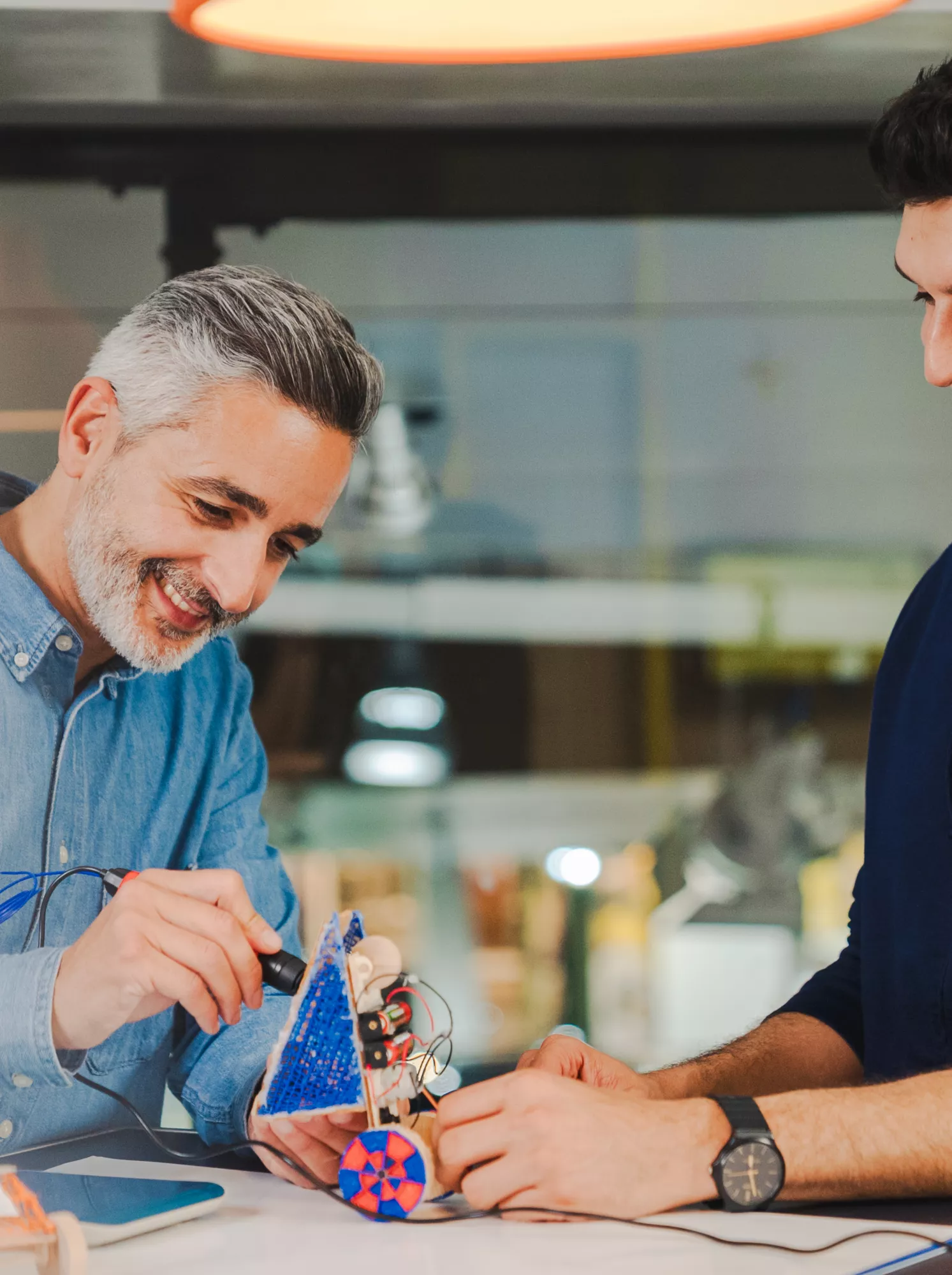 BMW Welt Workshop‑Leiter und Teilnehmer arbeiten gemeinsam an einer praktischen Aufgabe zu Zukunftsmobilität und Nachhaltigkeit.