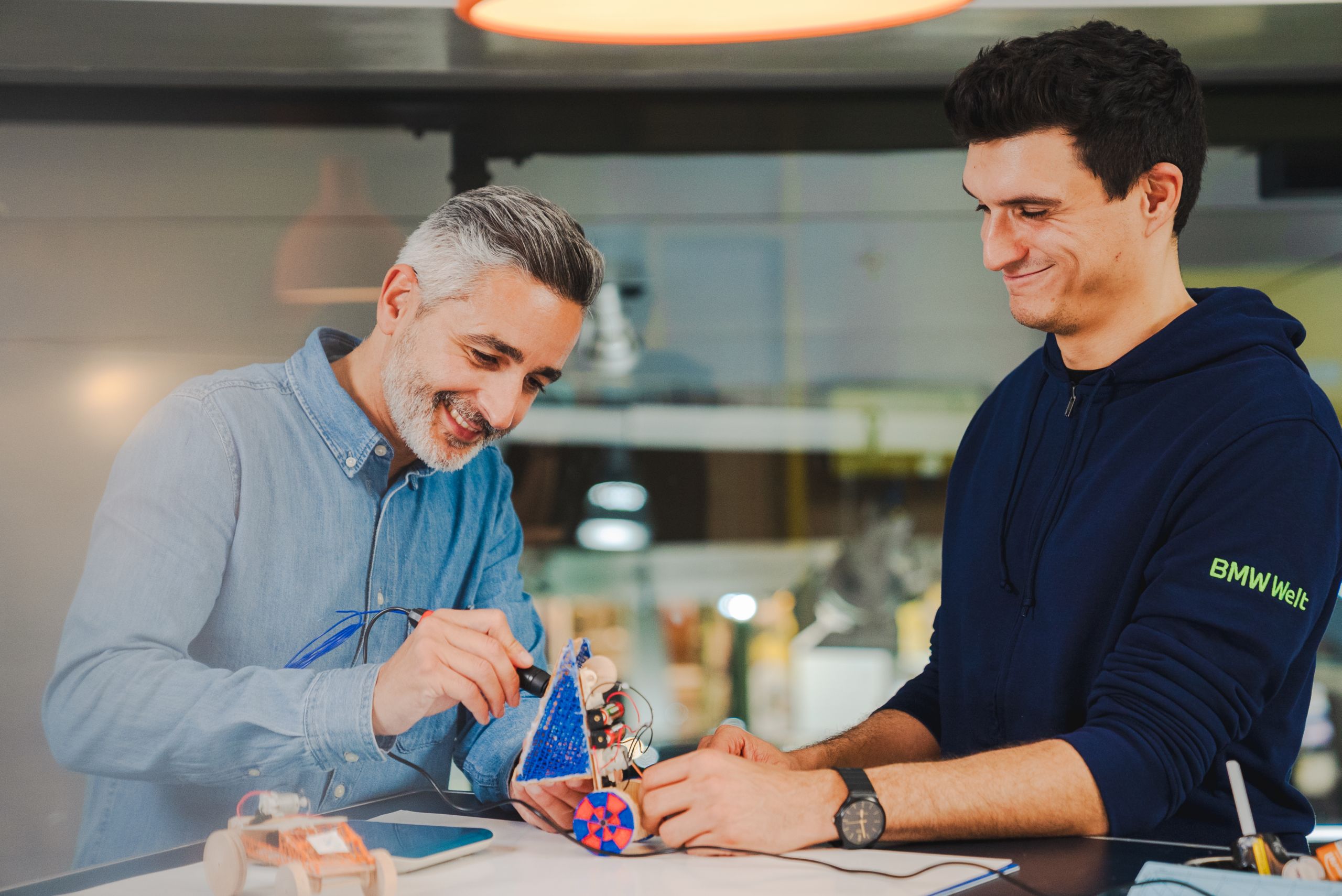 BMW Welt workshop instructor guiding a participant during a hands‑on sustainability and mobility workshop.