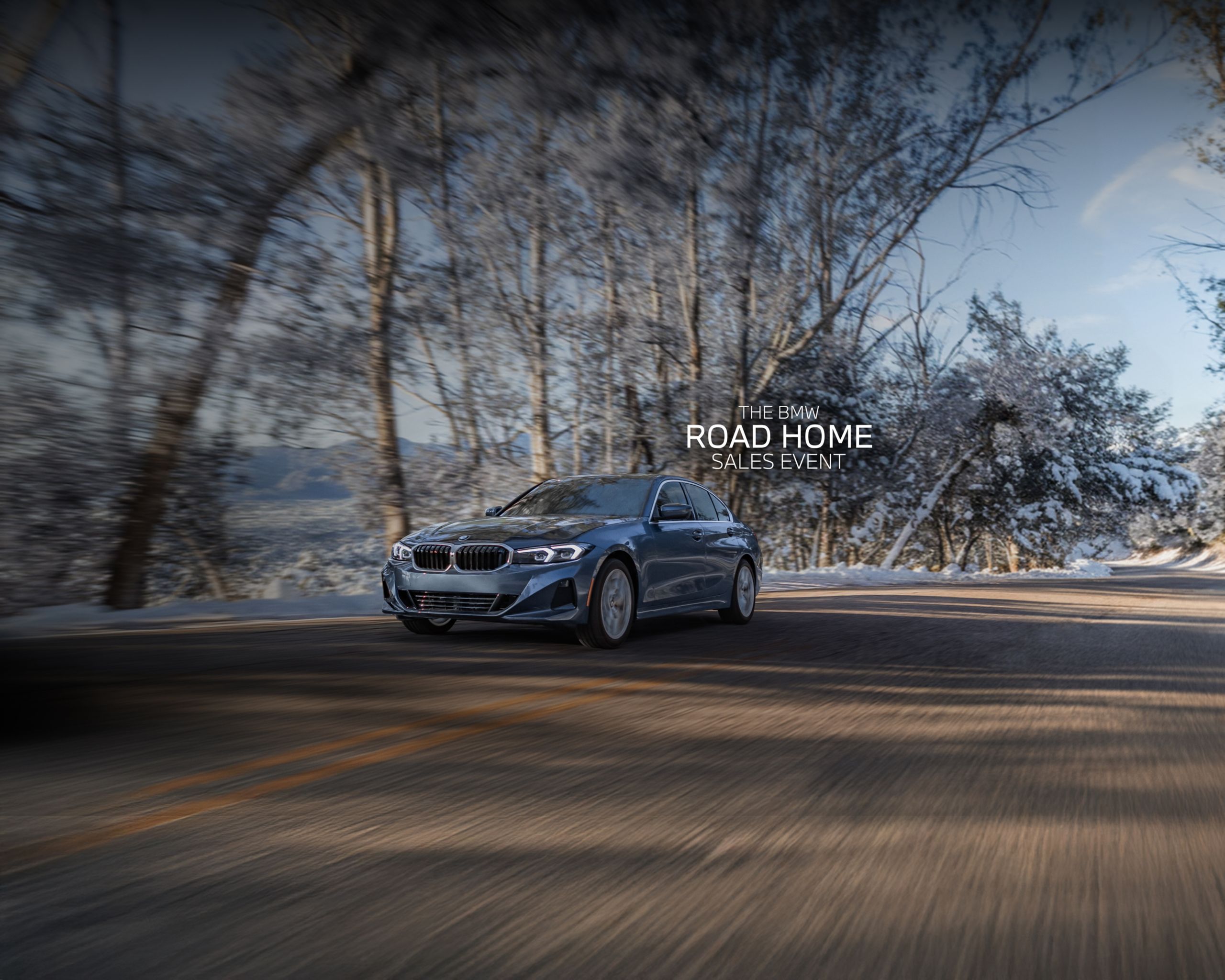 Dynamic shot of a 2026 BMW 330i xDrive driving on a tree-lined road