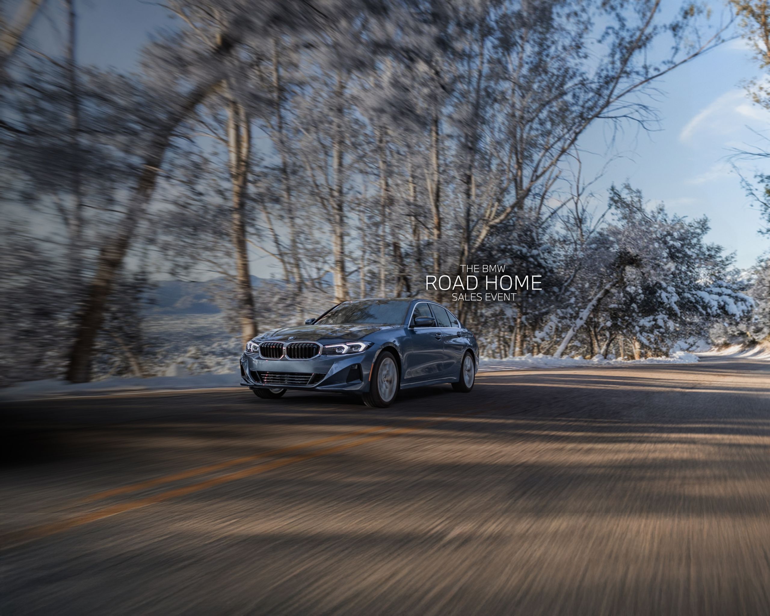 Dynamic shot of a 2026 BMW 330i xDrive driving on a tree-lined road