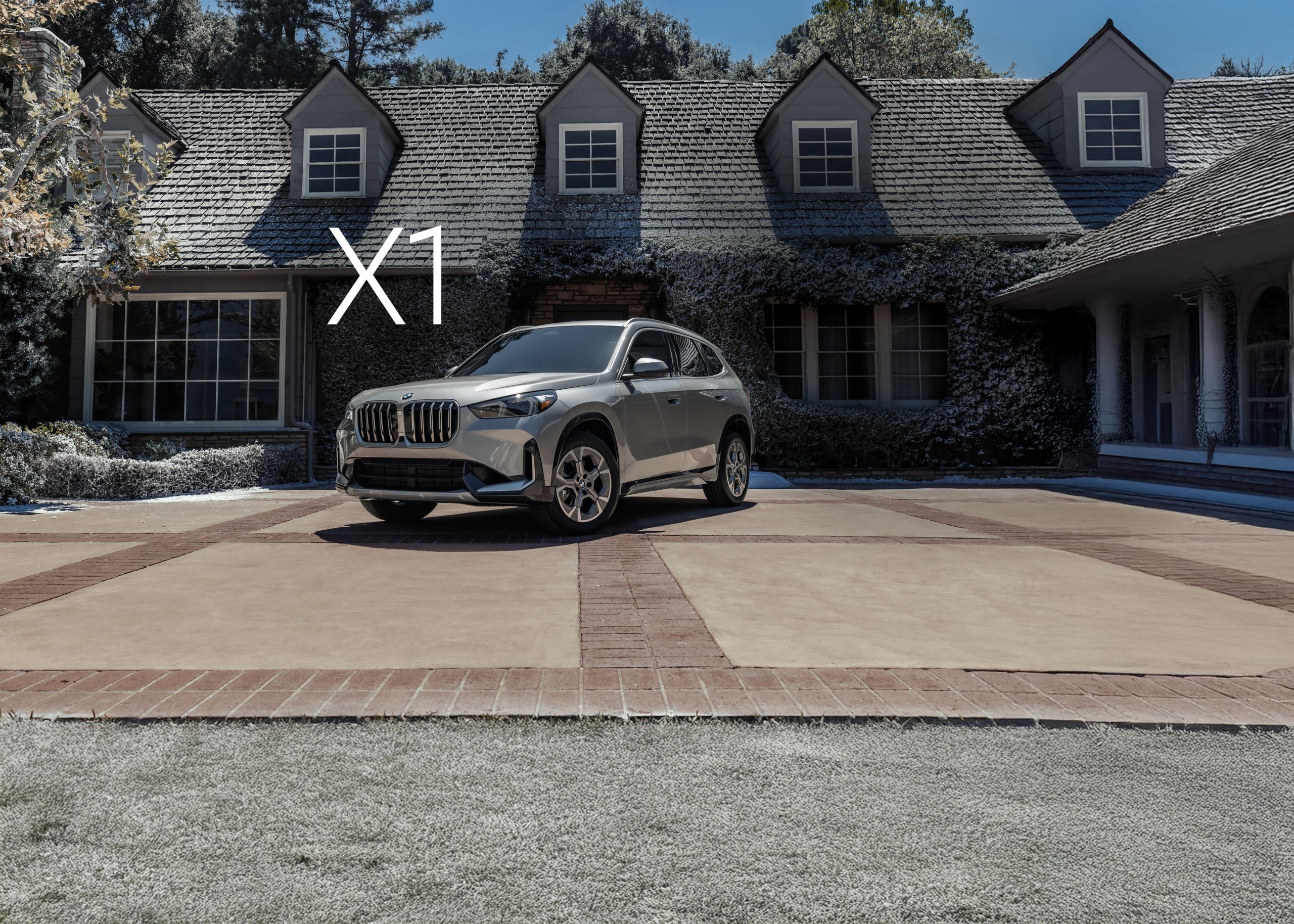 A 2026 BMW X1 xDrive28i parked in front of an idyllic snow-covered home