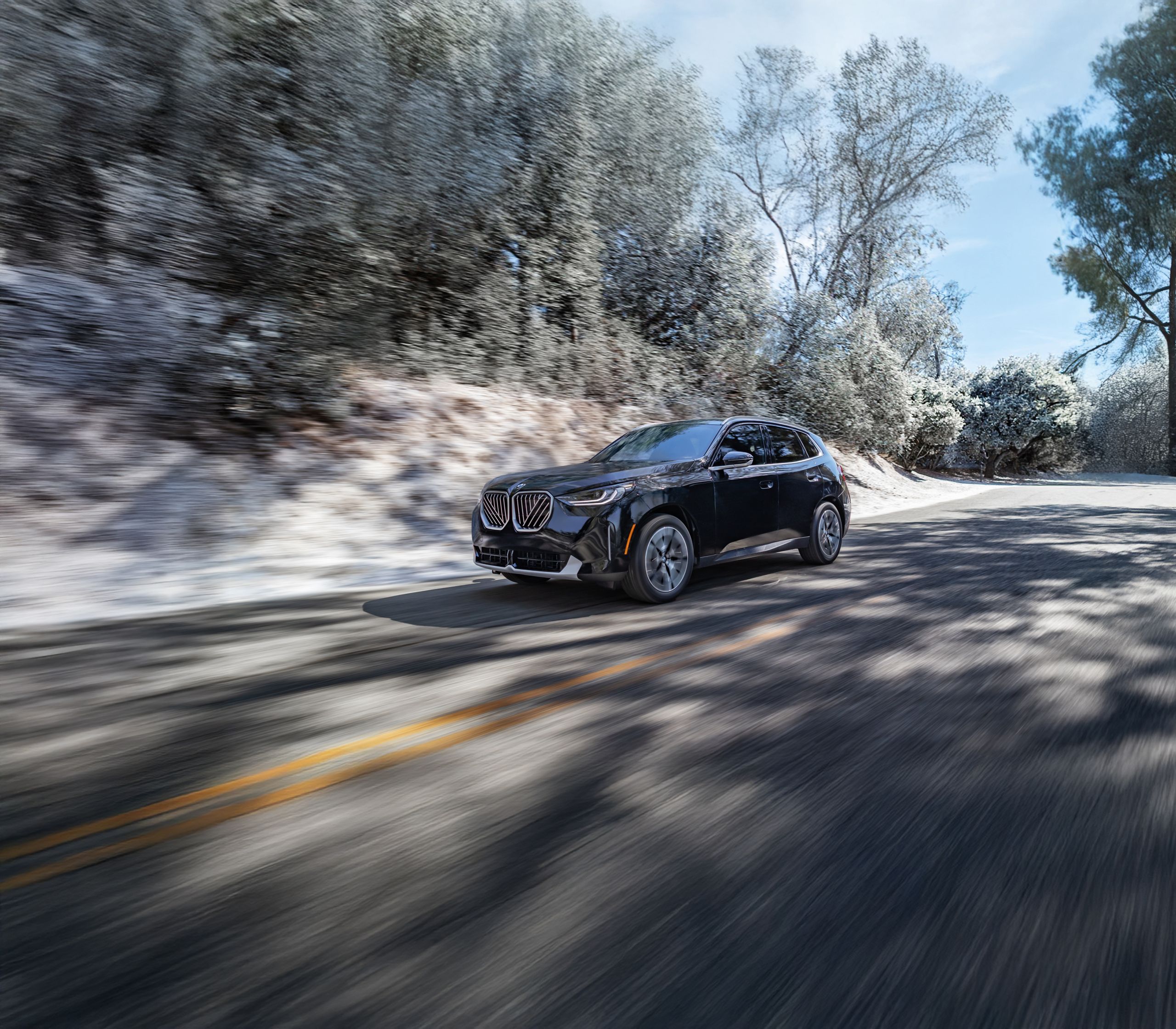 Dynamic shot of a 2026 BMW X3 30 xDrive cruising down a road