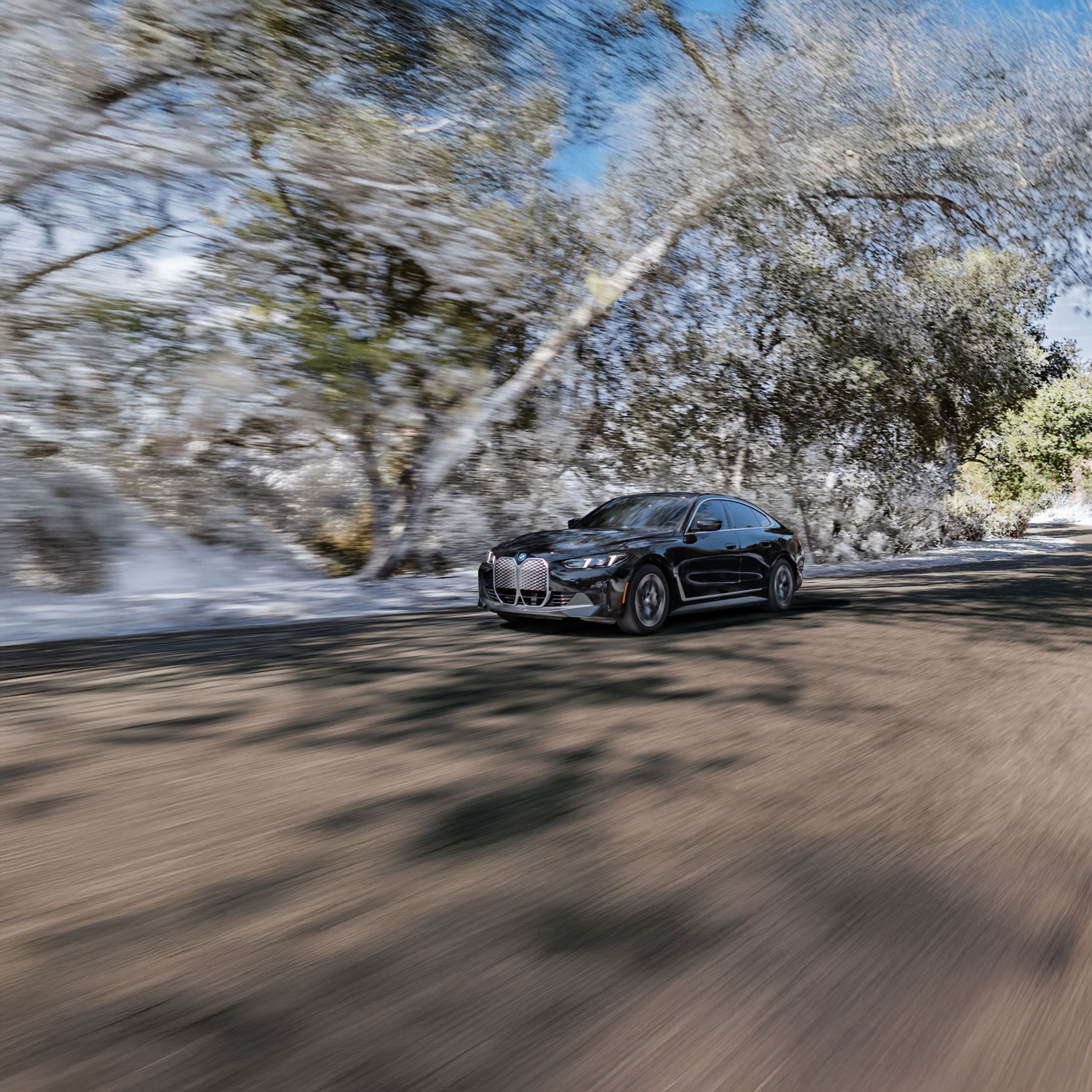 Dynamic shot of a 2025 BMW i4 eDrive40 Gran Coupe cruising down a wintery road